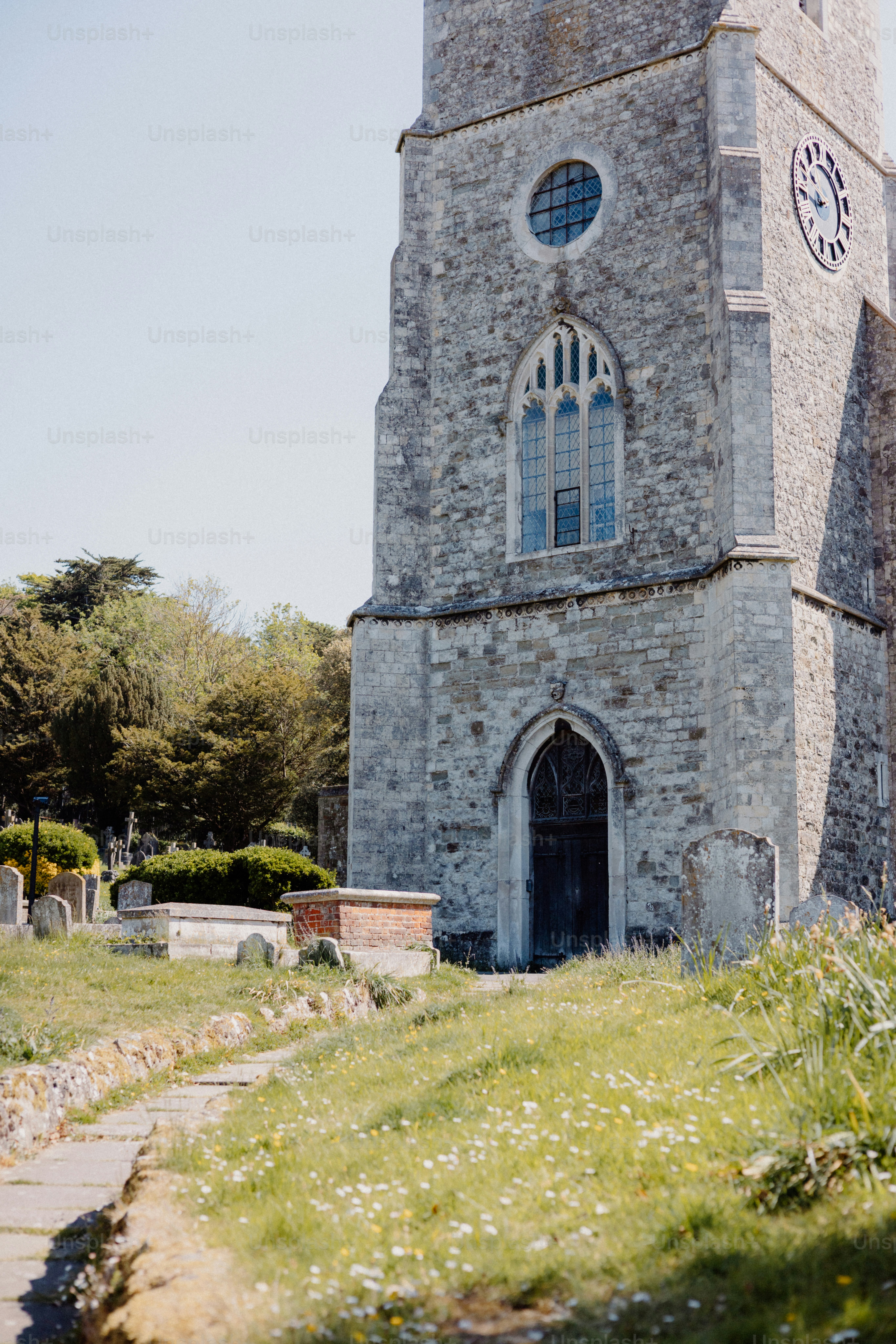 A tall stone church tower stands next to a graveyard.