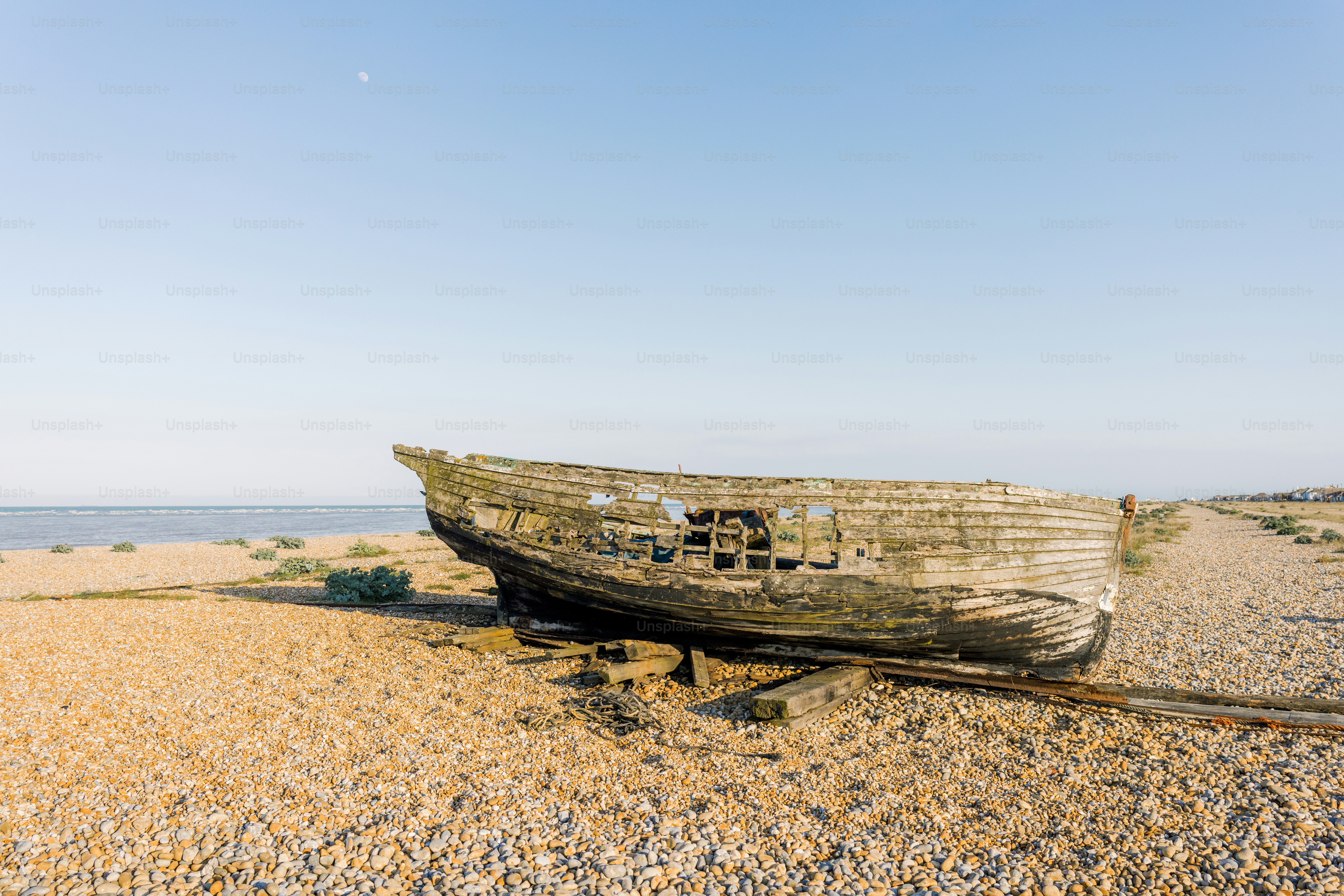 Old, weathered boat sits on a sandy beach.