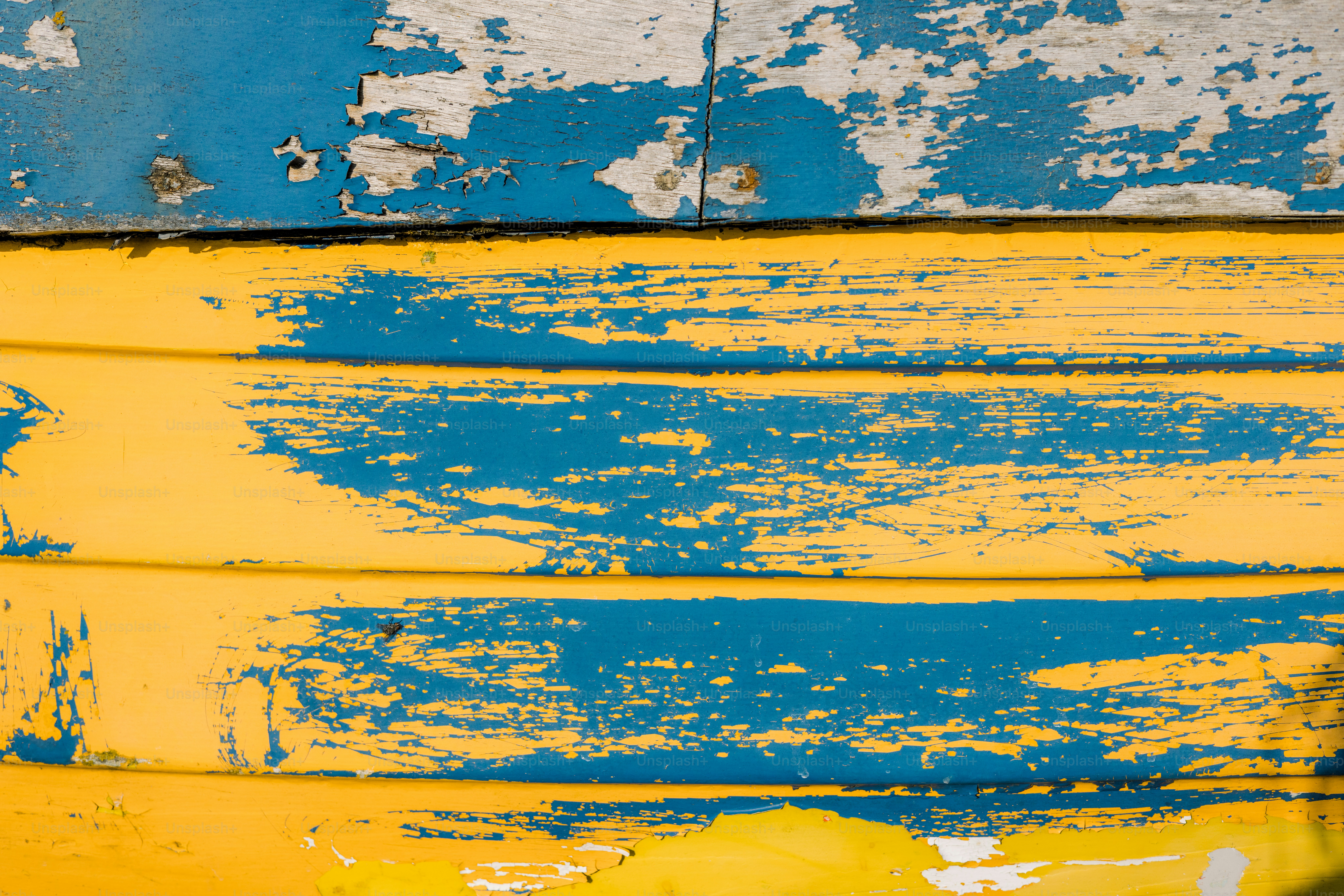 Blue and yellow paint peeling off of wood.