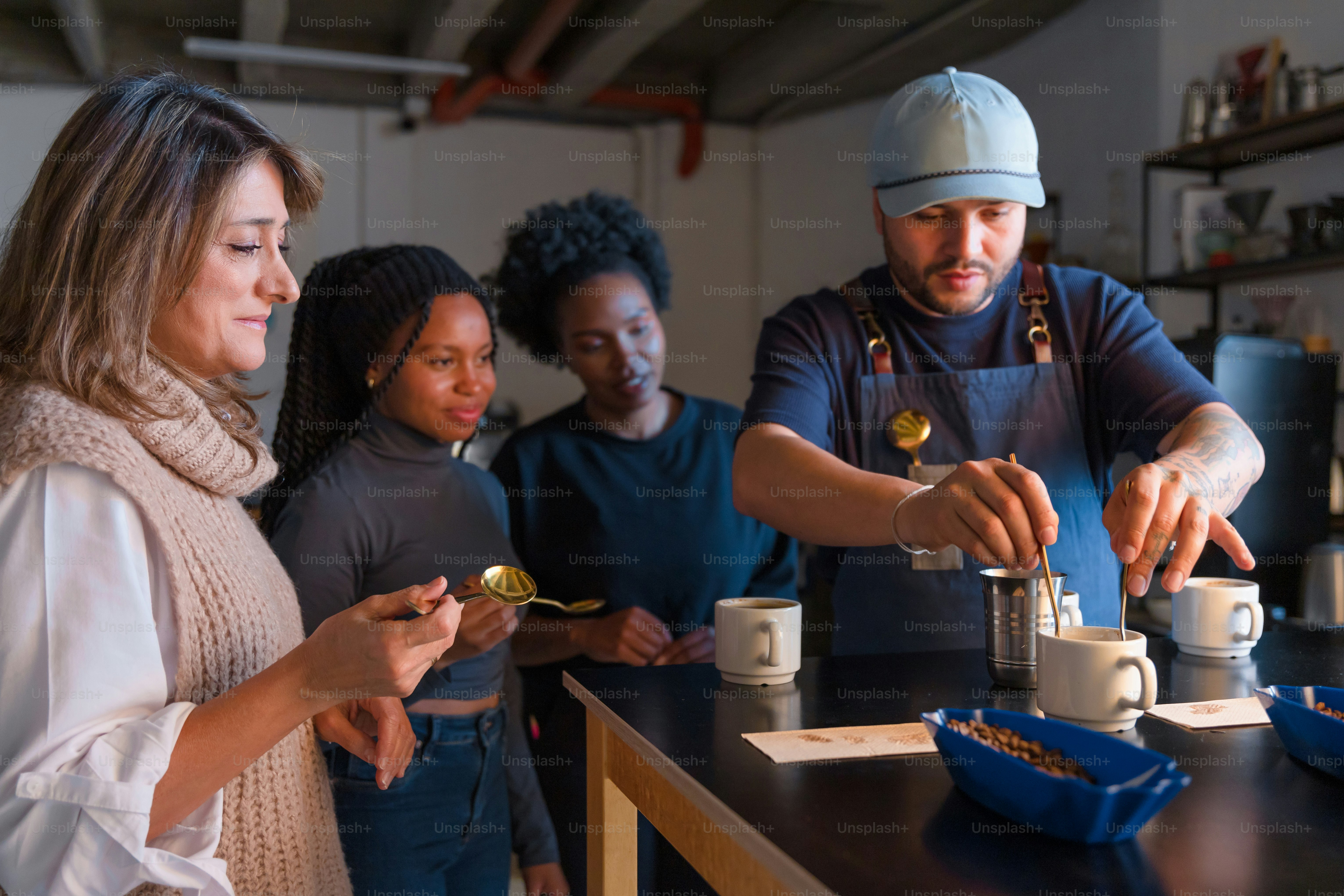 A barista prepares coffee for some waiting customers. photo – Coffee ...