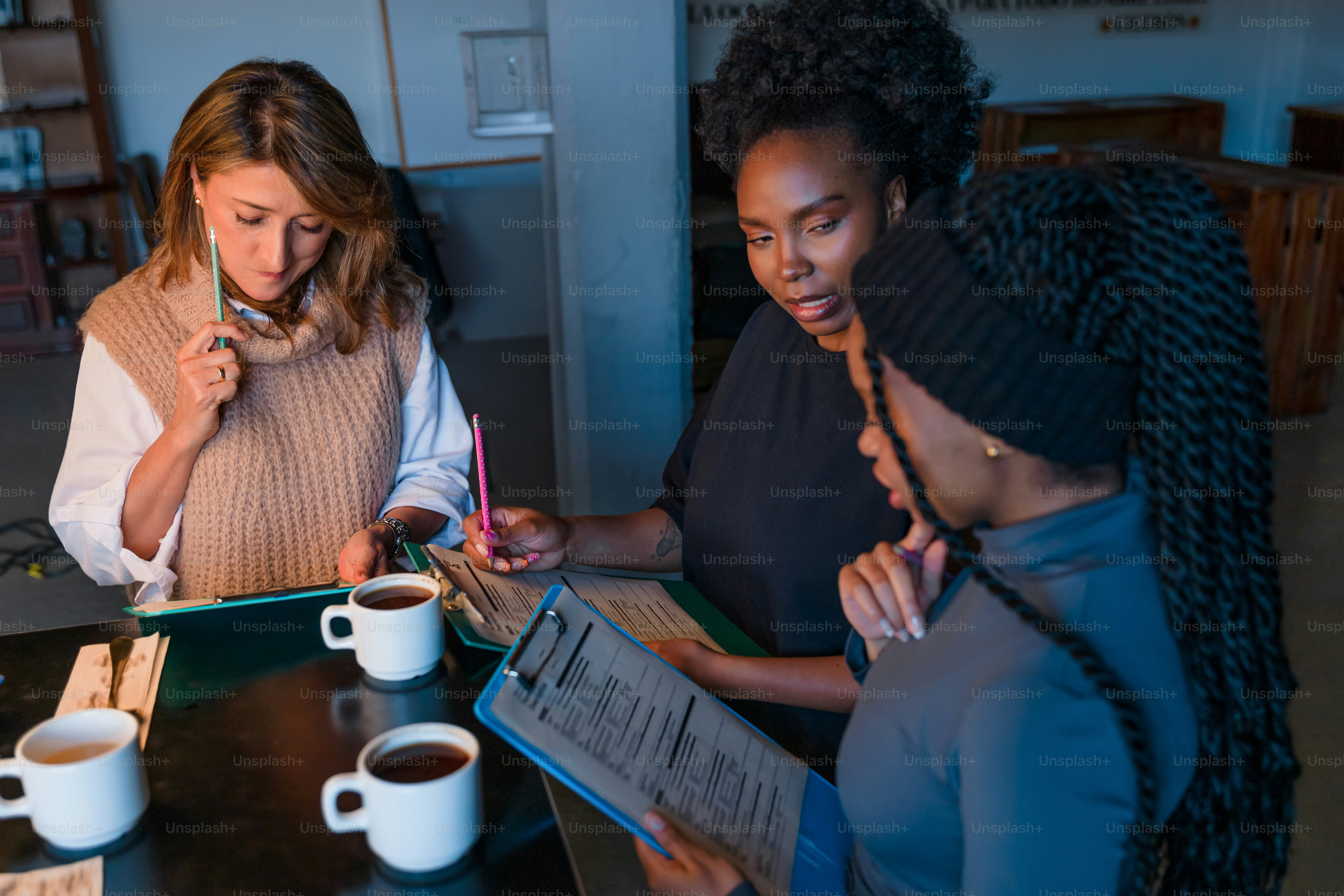 Tres mujeres colaboran entre documentos y café.