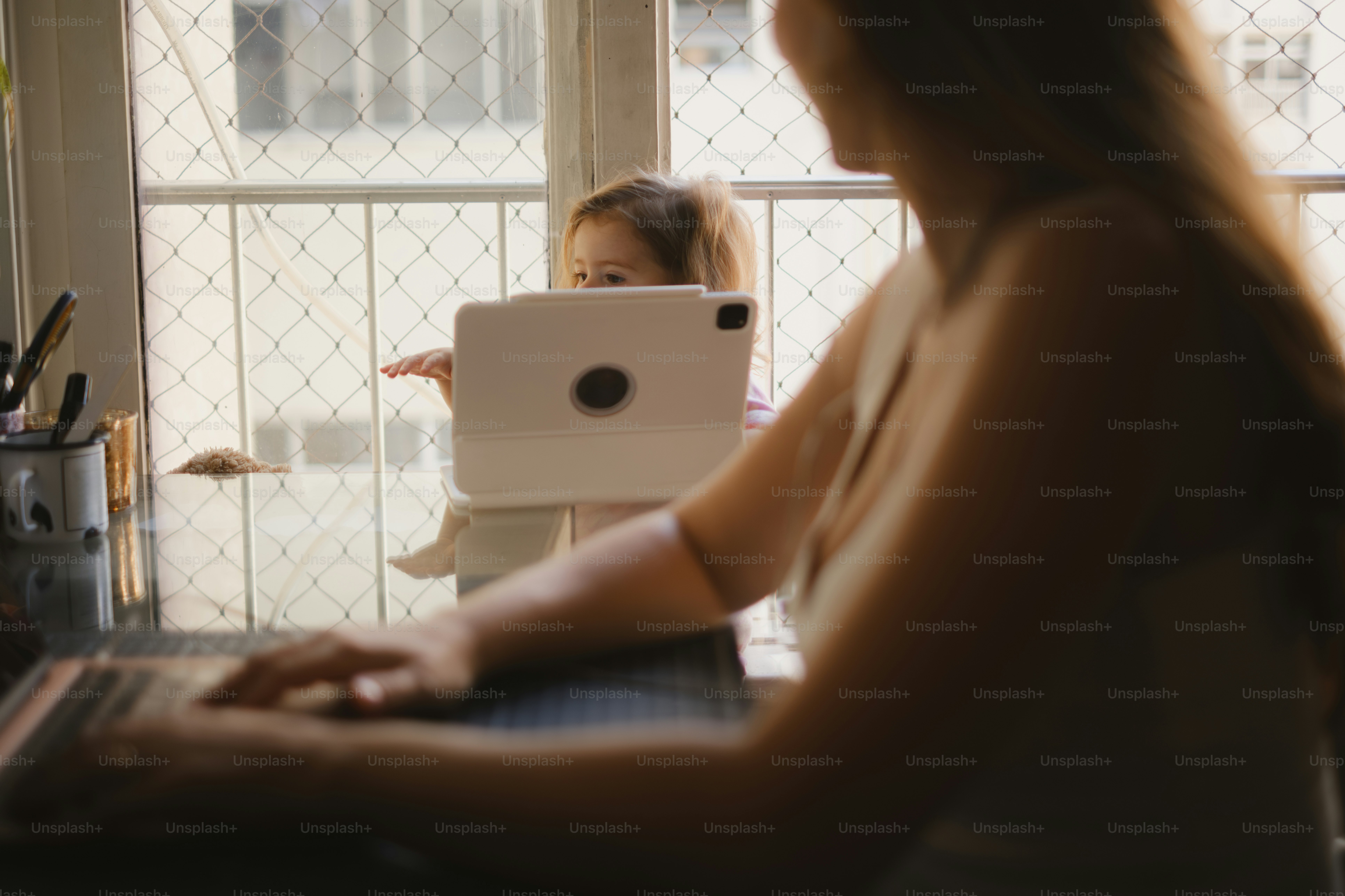 Mother works while child plays with a tablet.
