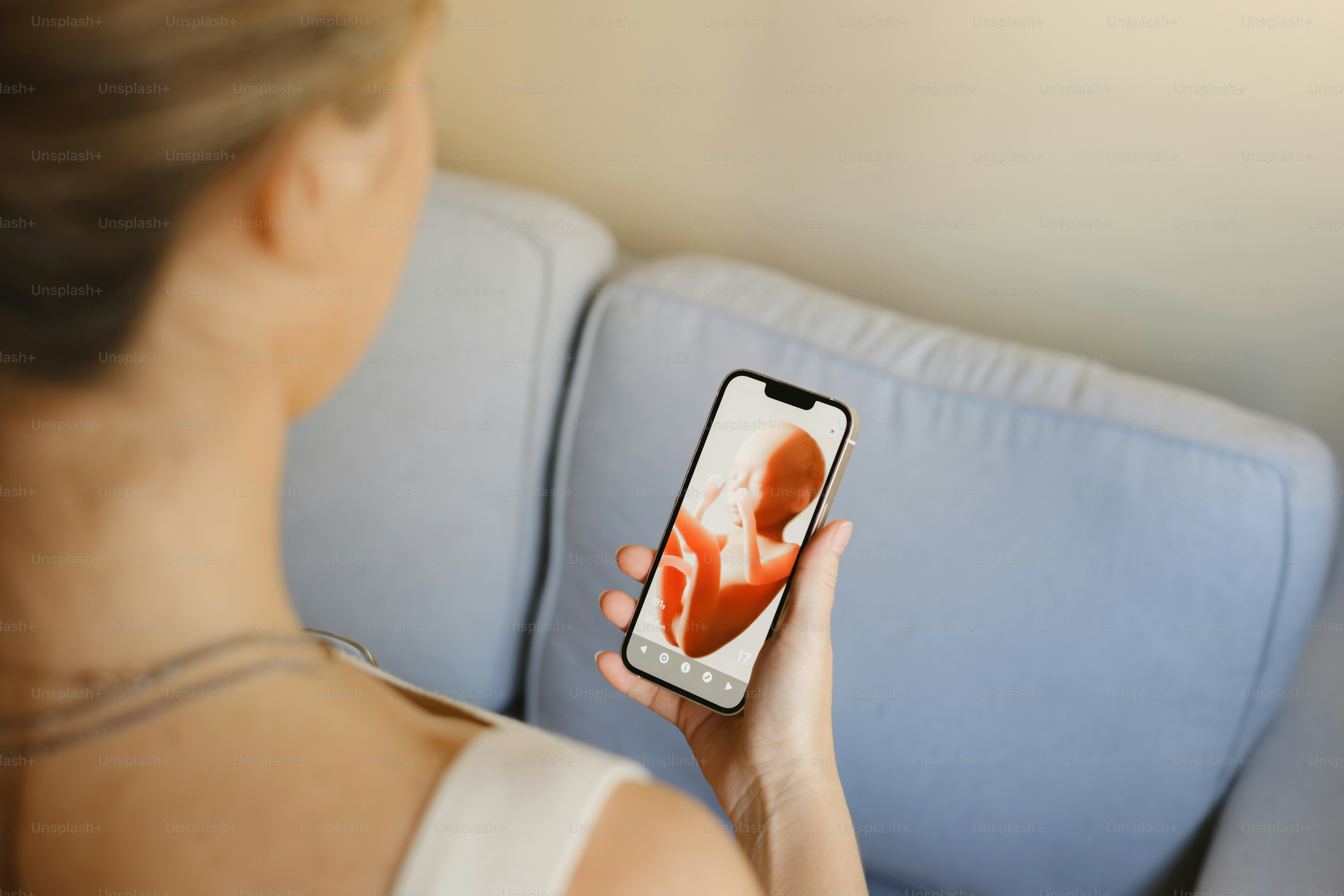 A woman looks at an ultrasound on her phone.