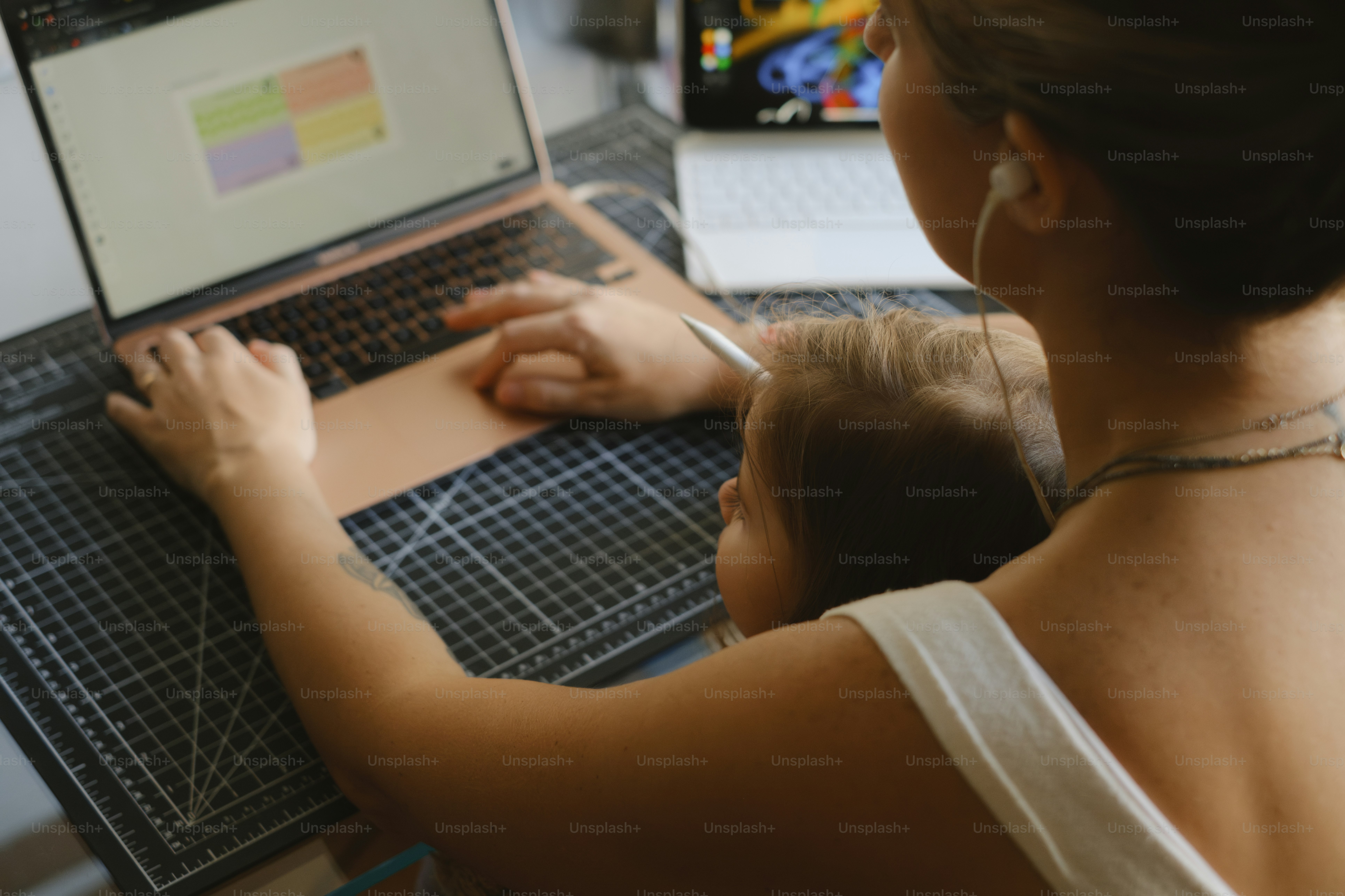 Woman works on laptop with a child.
