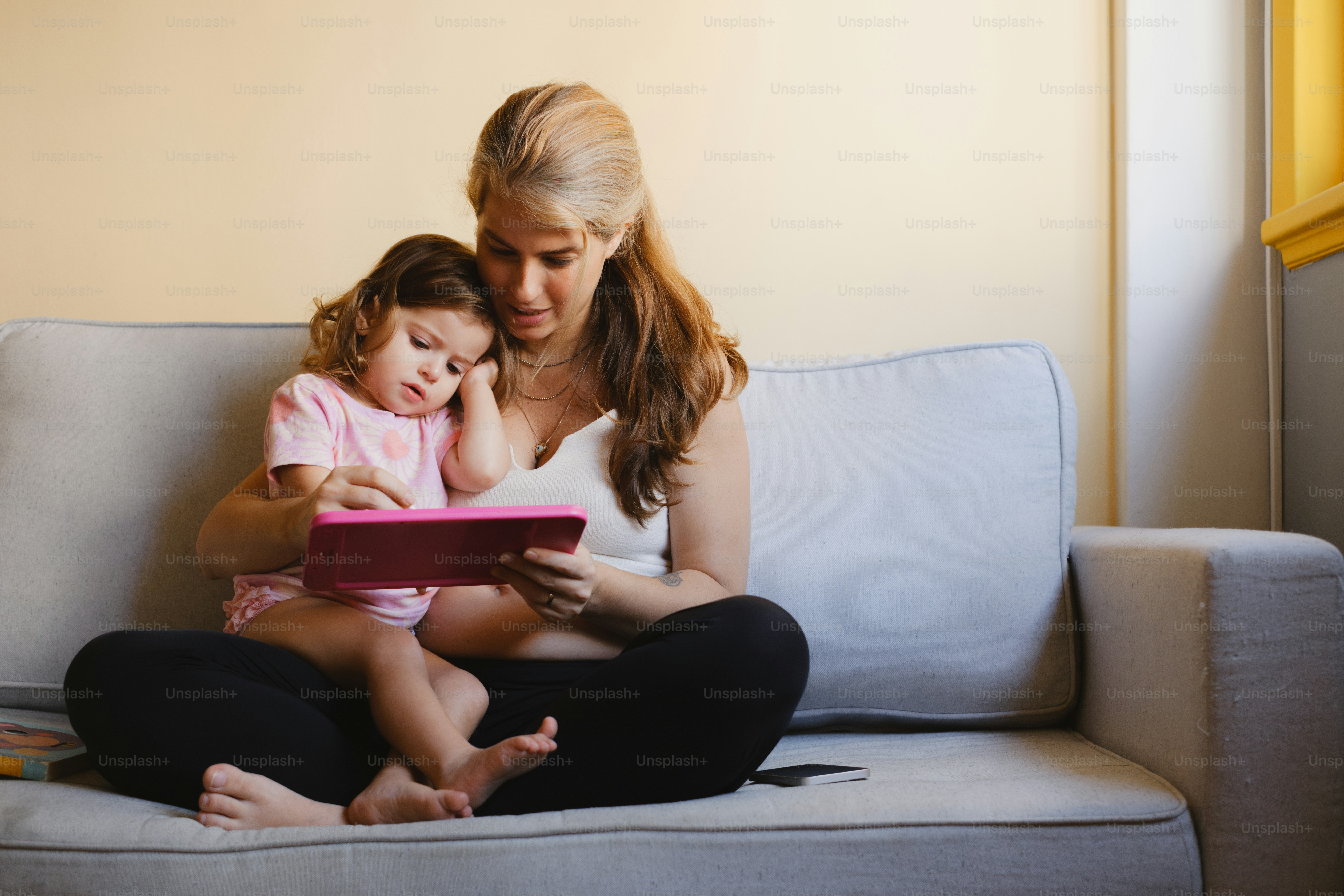 A mother and child read a tablet together.