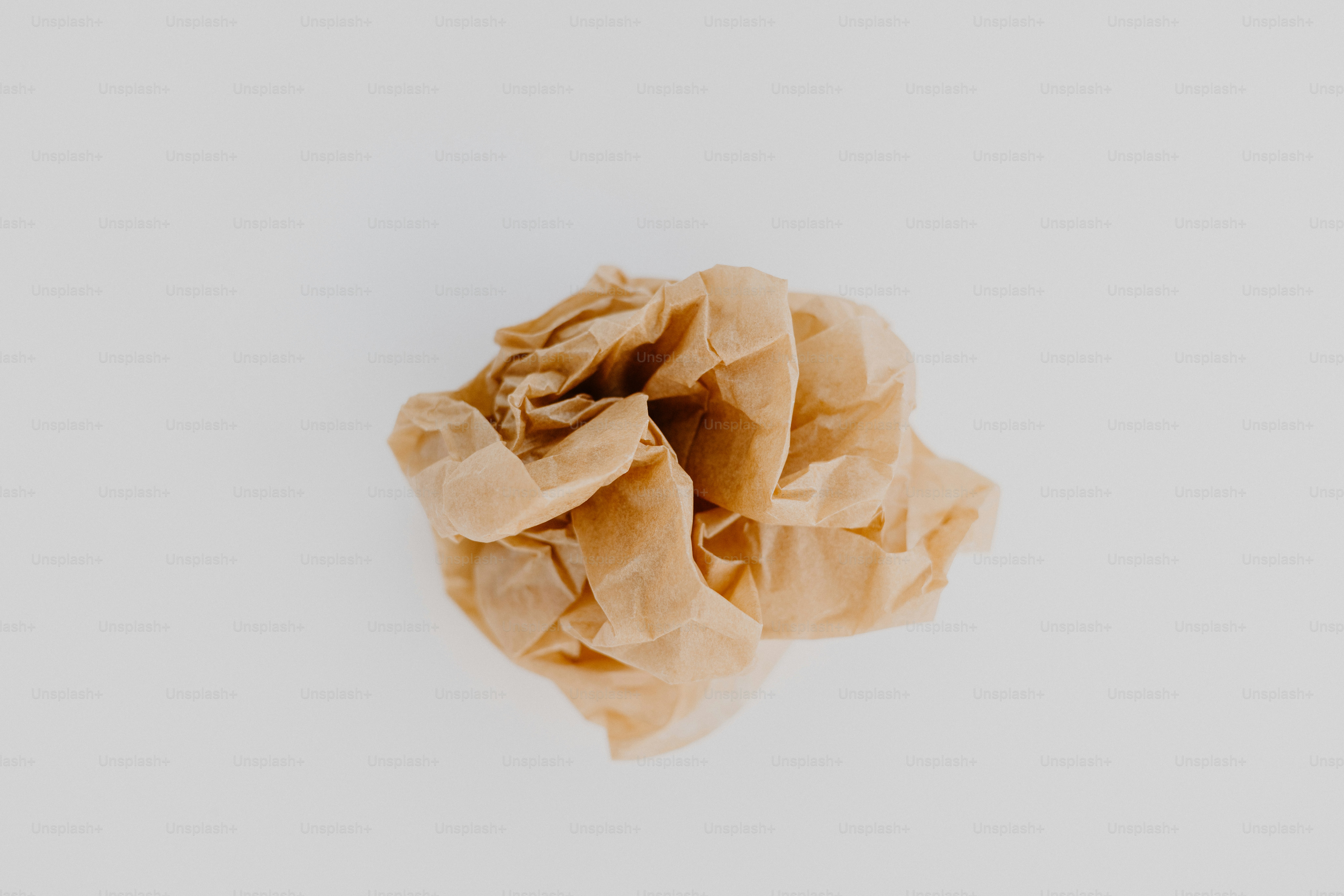Crumpled beige tissue paper on a white surface.