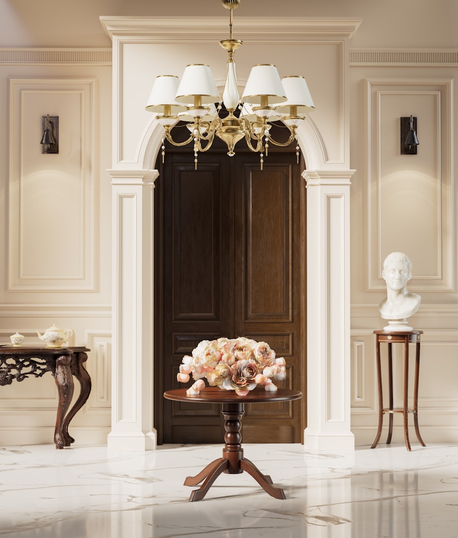 An elegant ivory foyer with brass chandelier, pink roses, and marble floor
