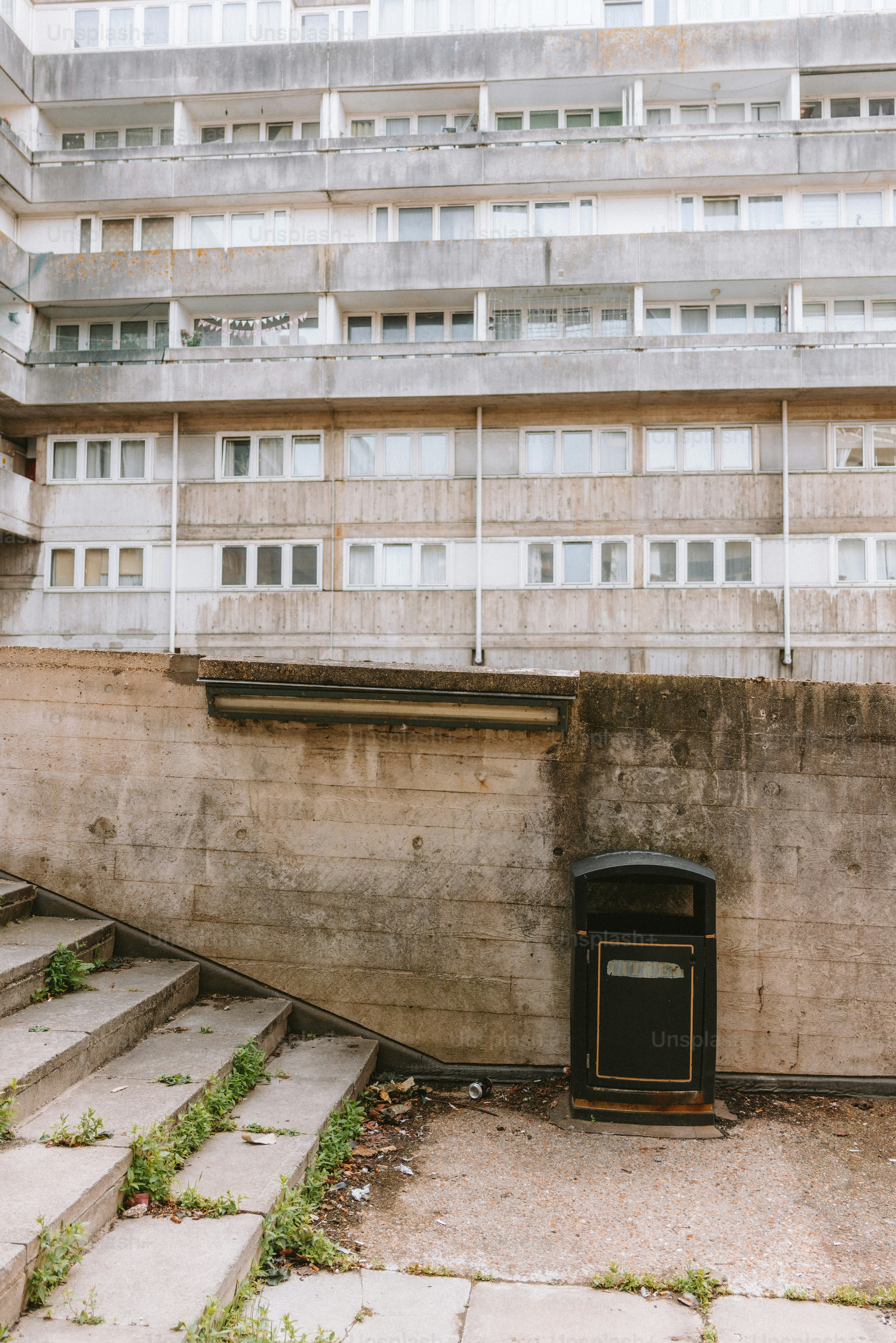 Concrete building and steps with a trash can.