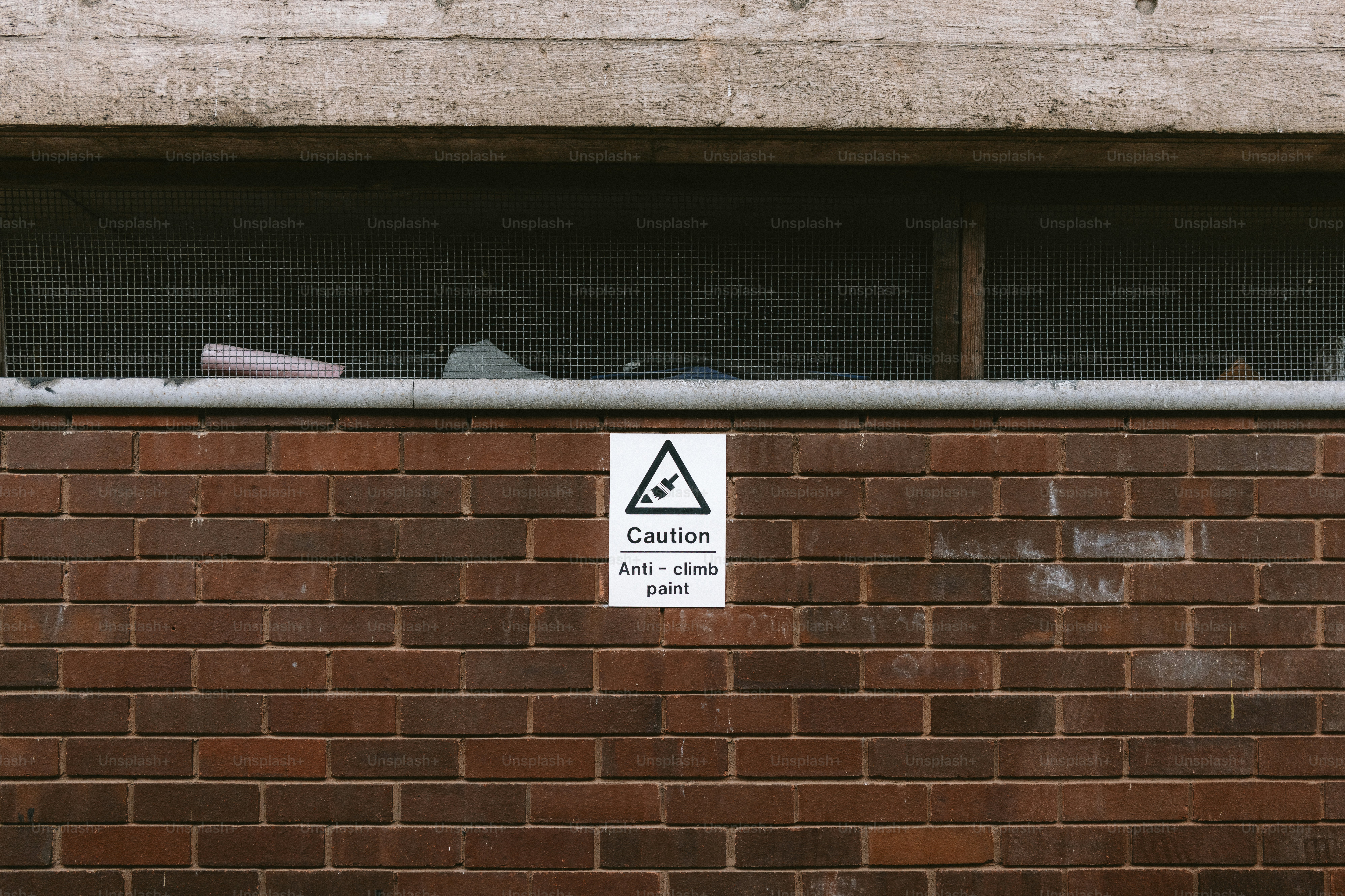 A brick wall with a caution sign. photo – Wall Image on Unsplash