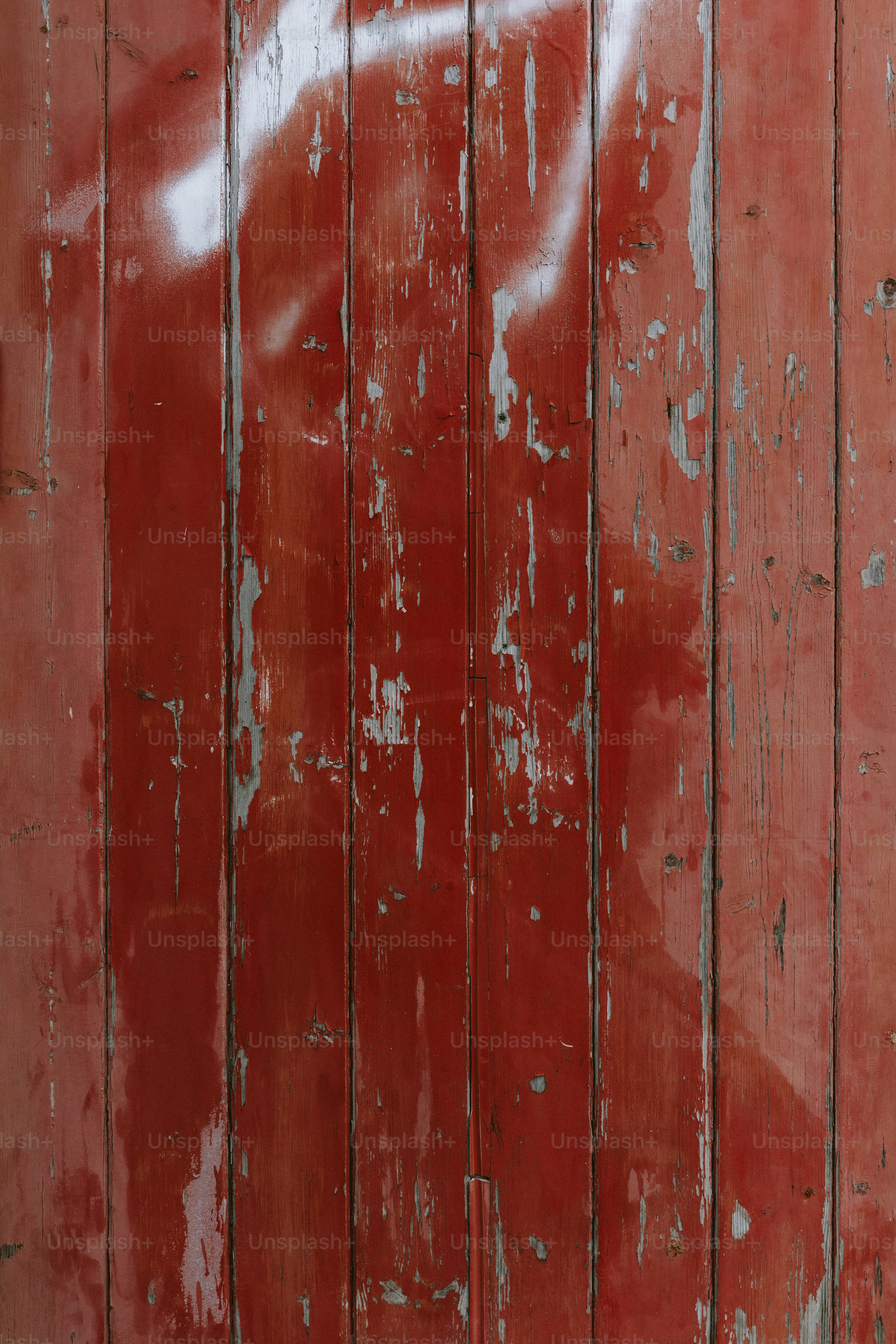 Verwitterte rote Holzbohlen zeigen abblätternde Farbe.