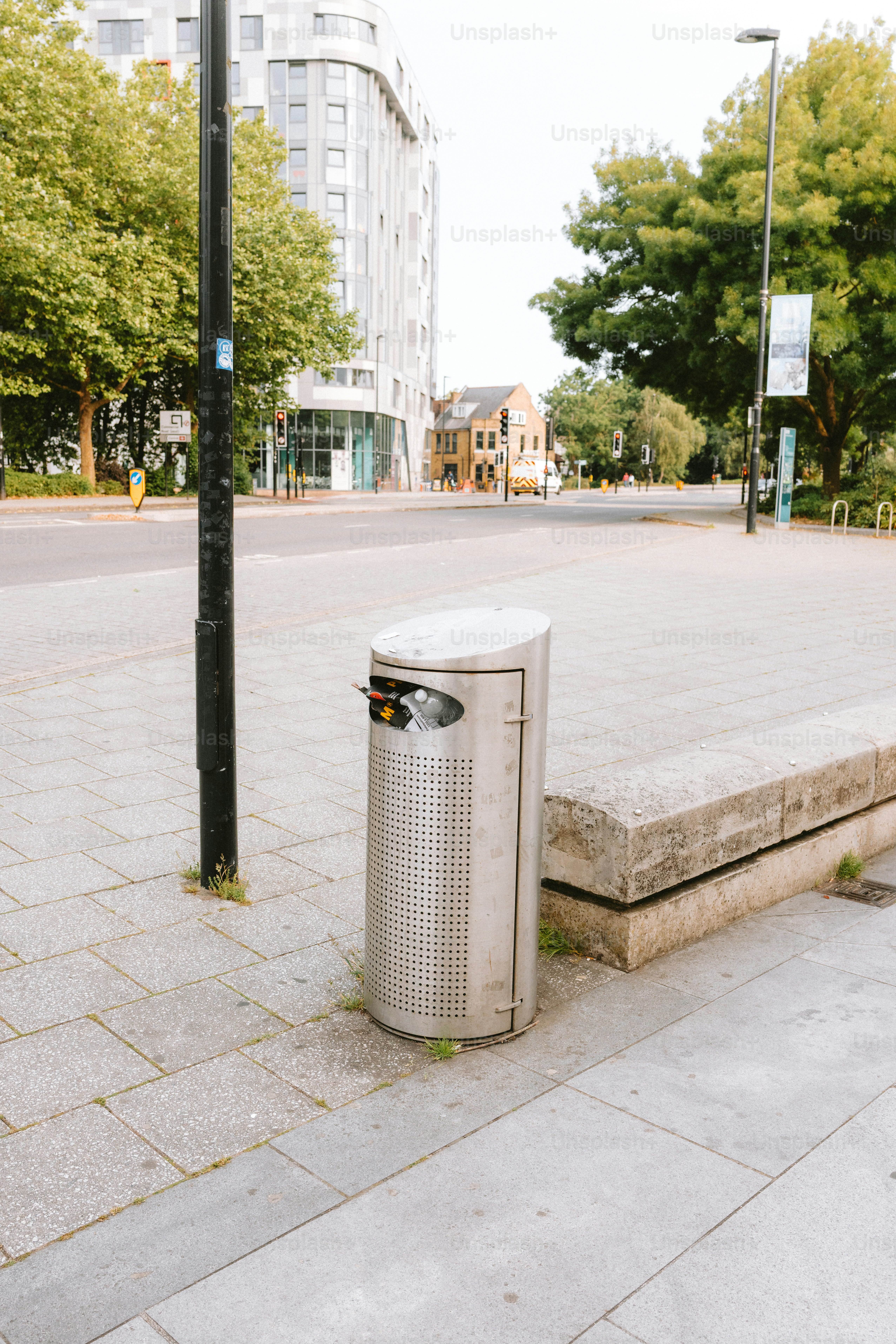 Un bote de basura de metal se encuentra en una acera de la ciudad.