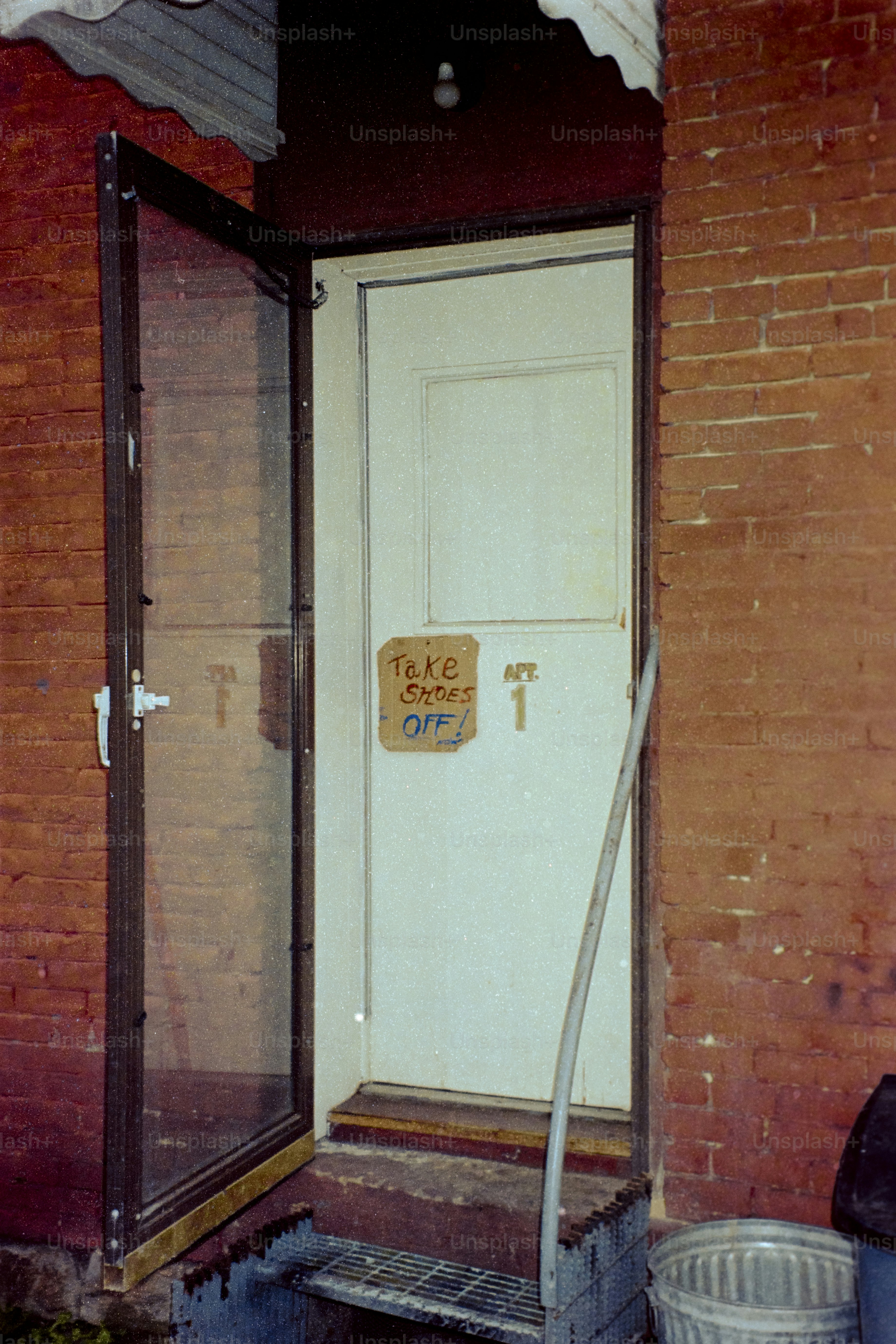 A screen door stands open next to a closed door.