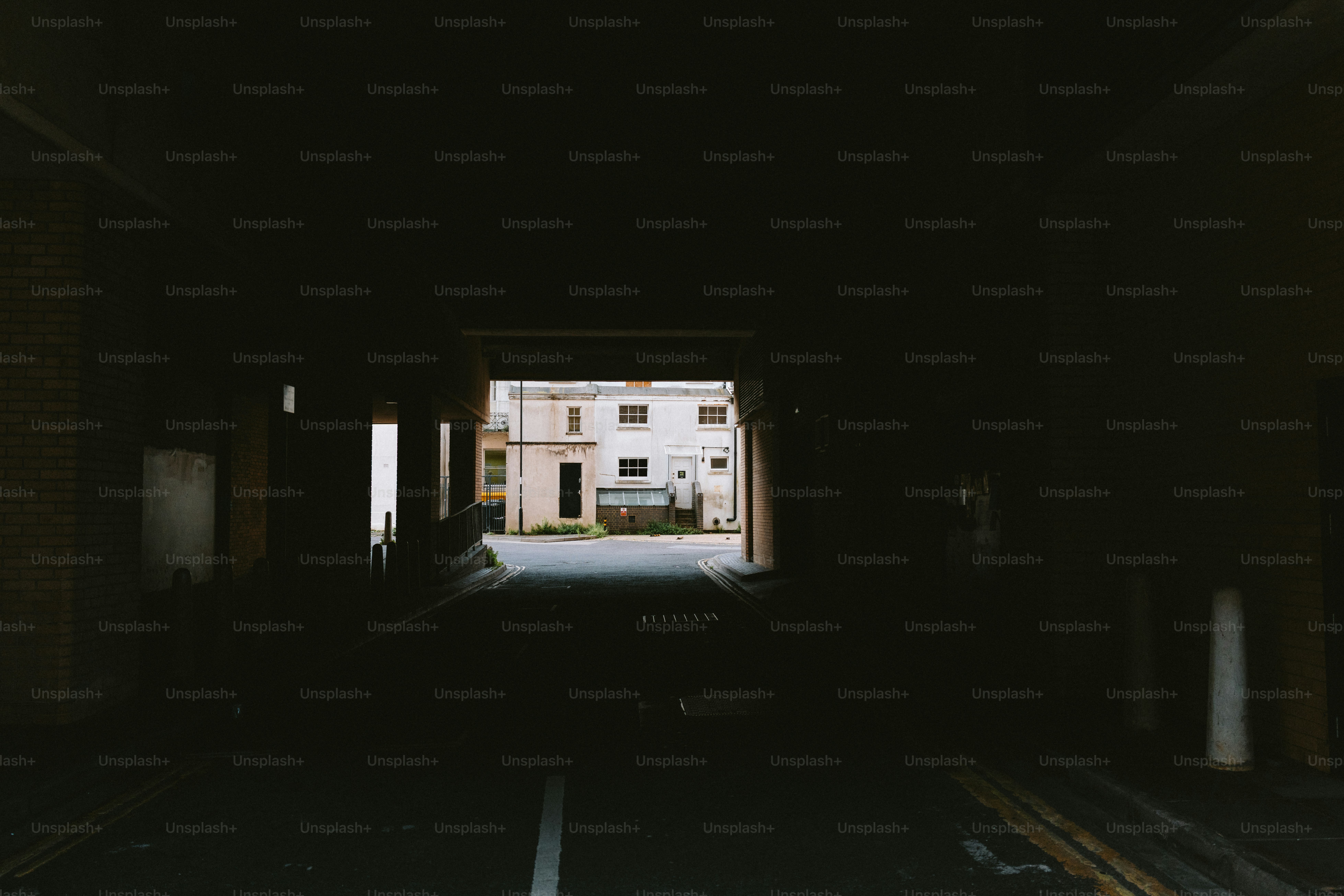 A dark tunnel leads to a bright building.