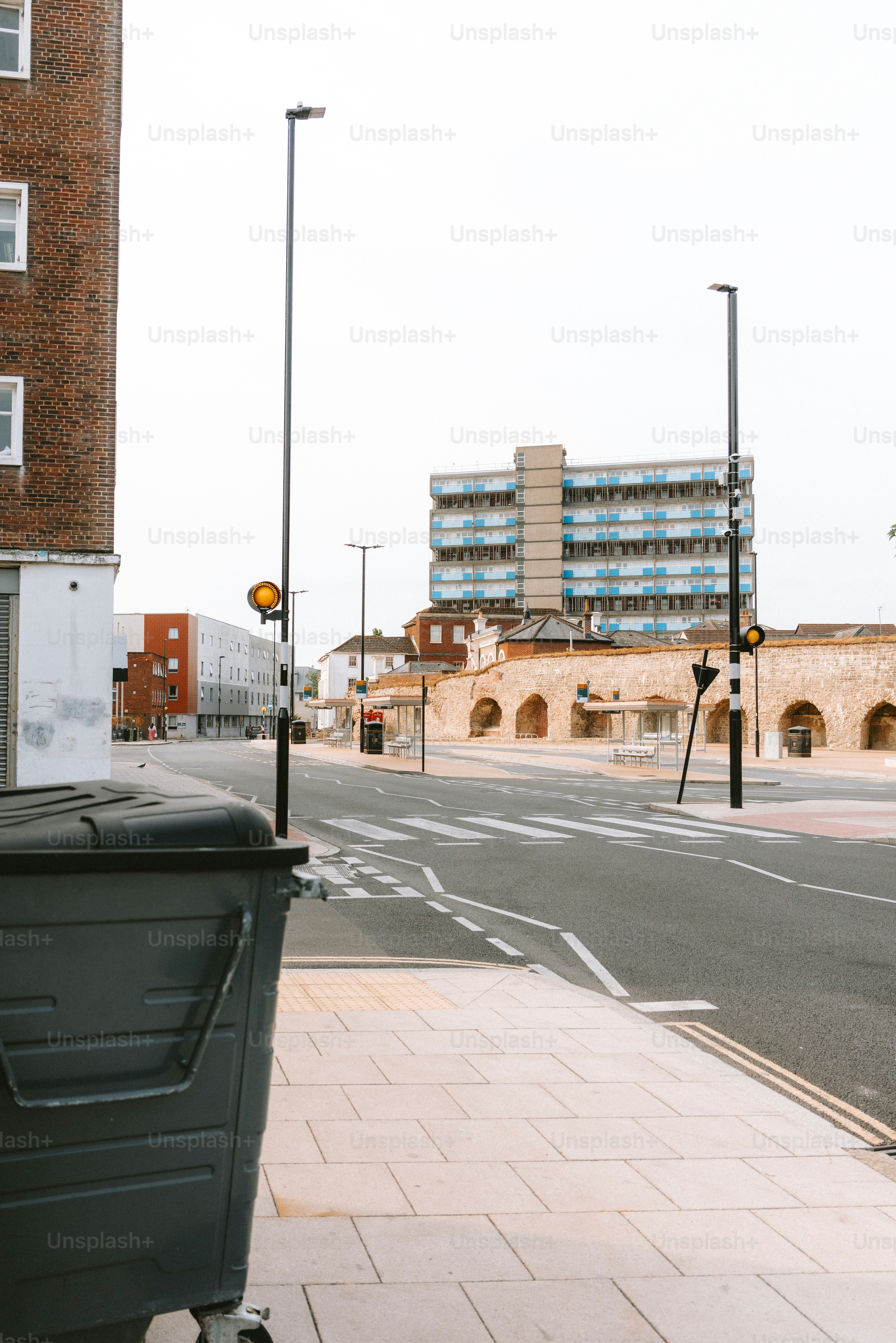 An urban street scene with buildings and a trash bin.