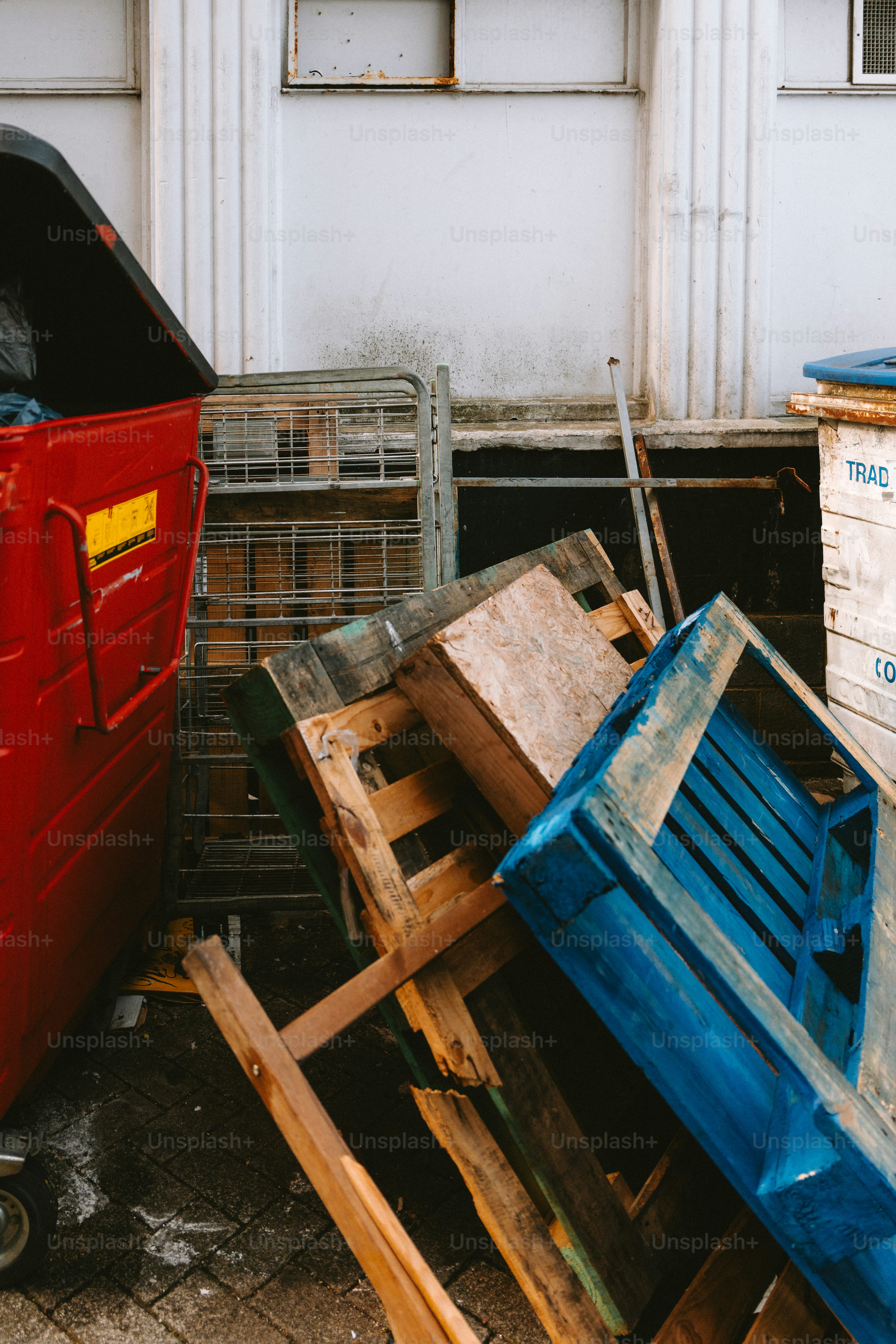 A red dumpster and discarded pallets.