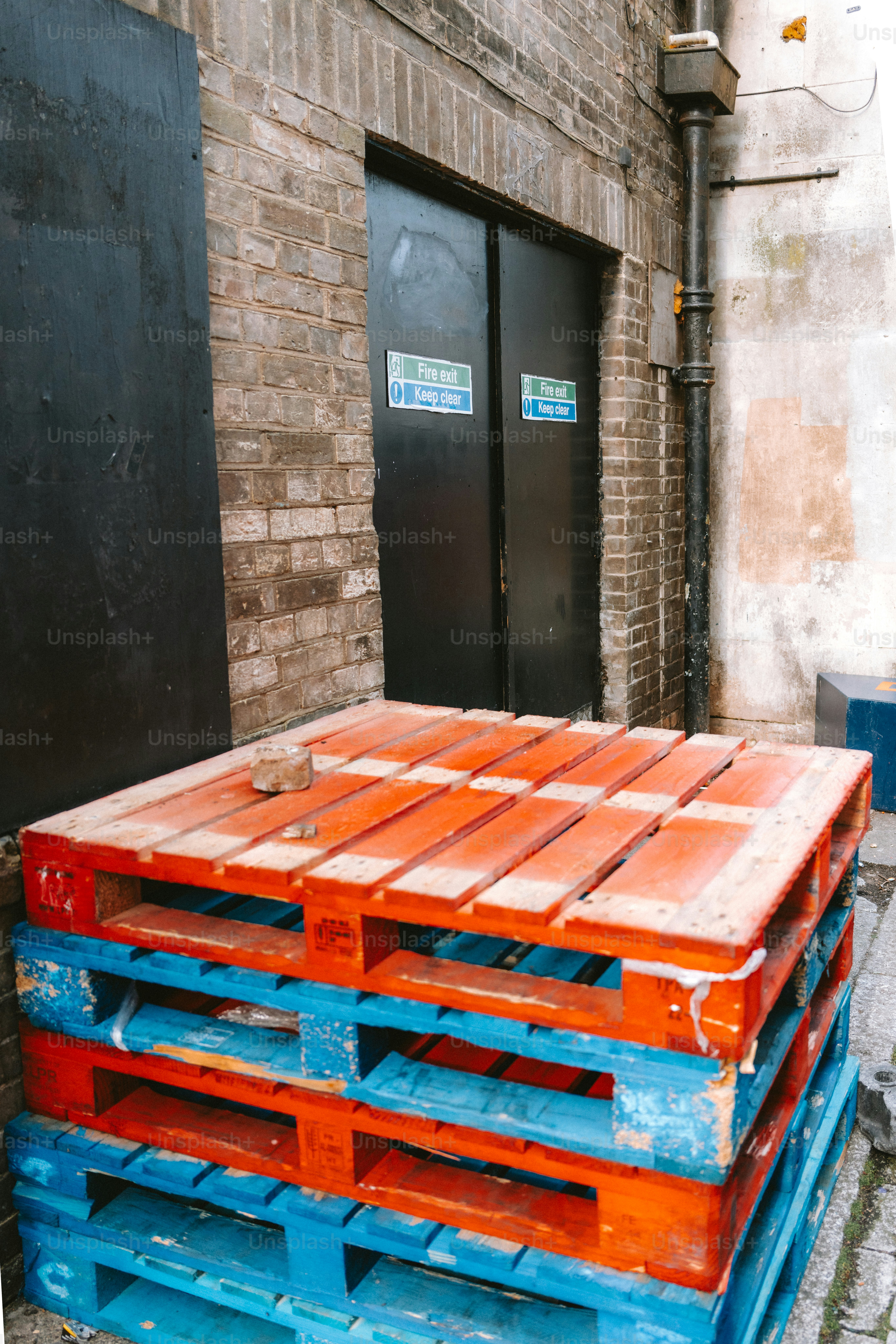 Pallets are stacked outside of a dark doorway.