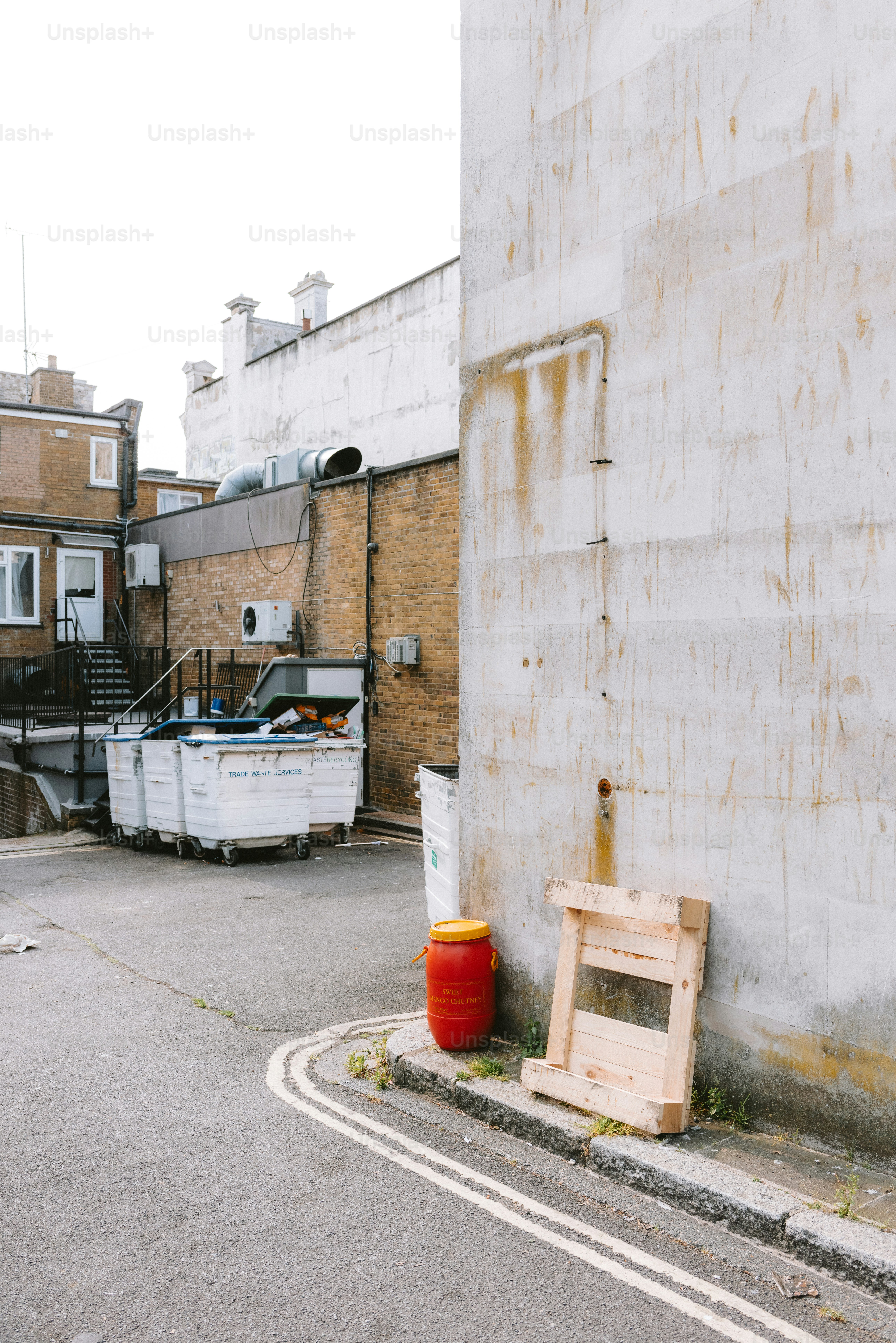 An alleyway features dumpsters, buildings, and a wooden structure.
