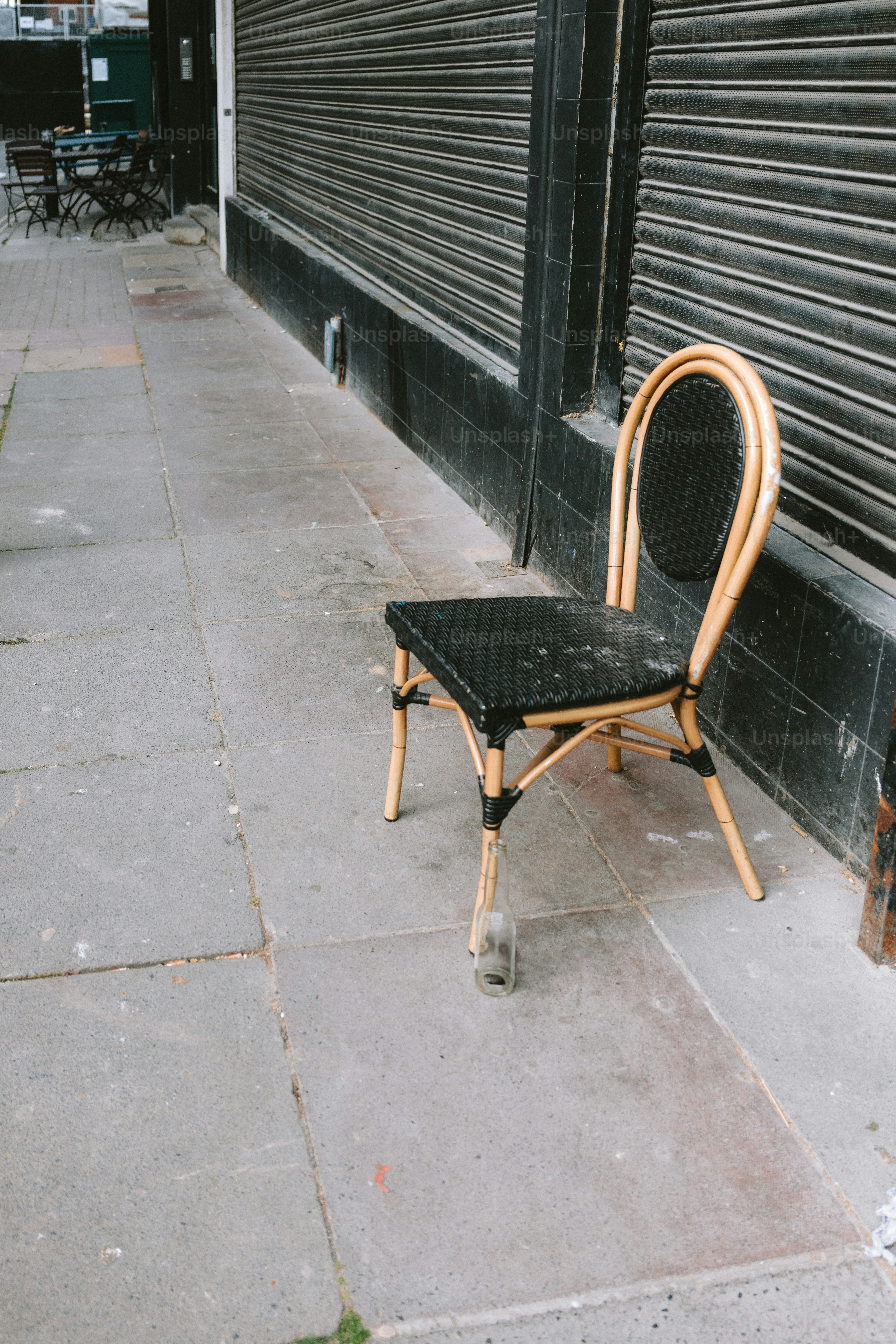 A chair sits on a sidewalk near a closed shop.