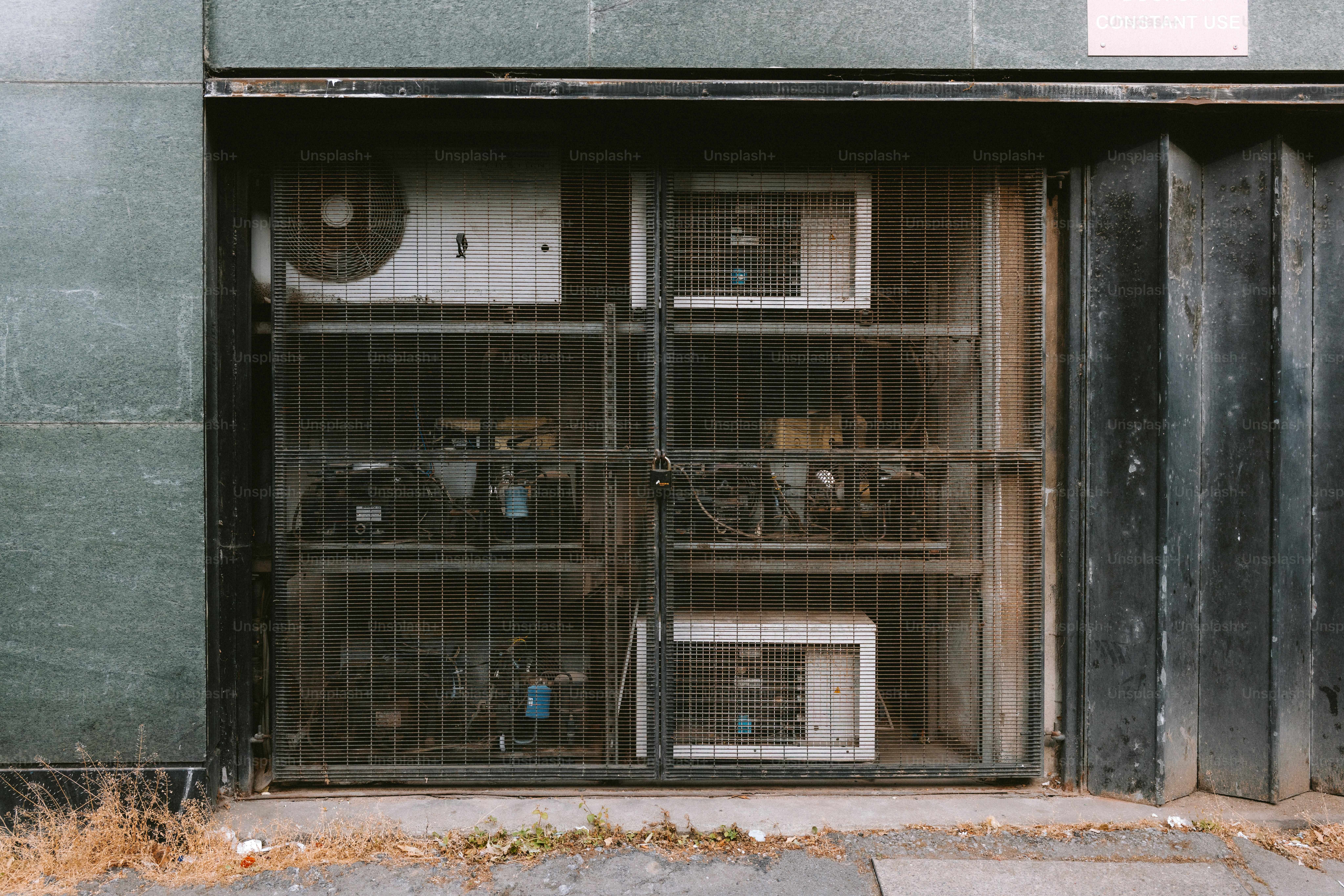 An air conditioning unit is behind a security gate.