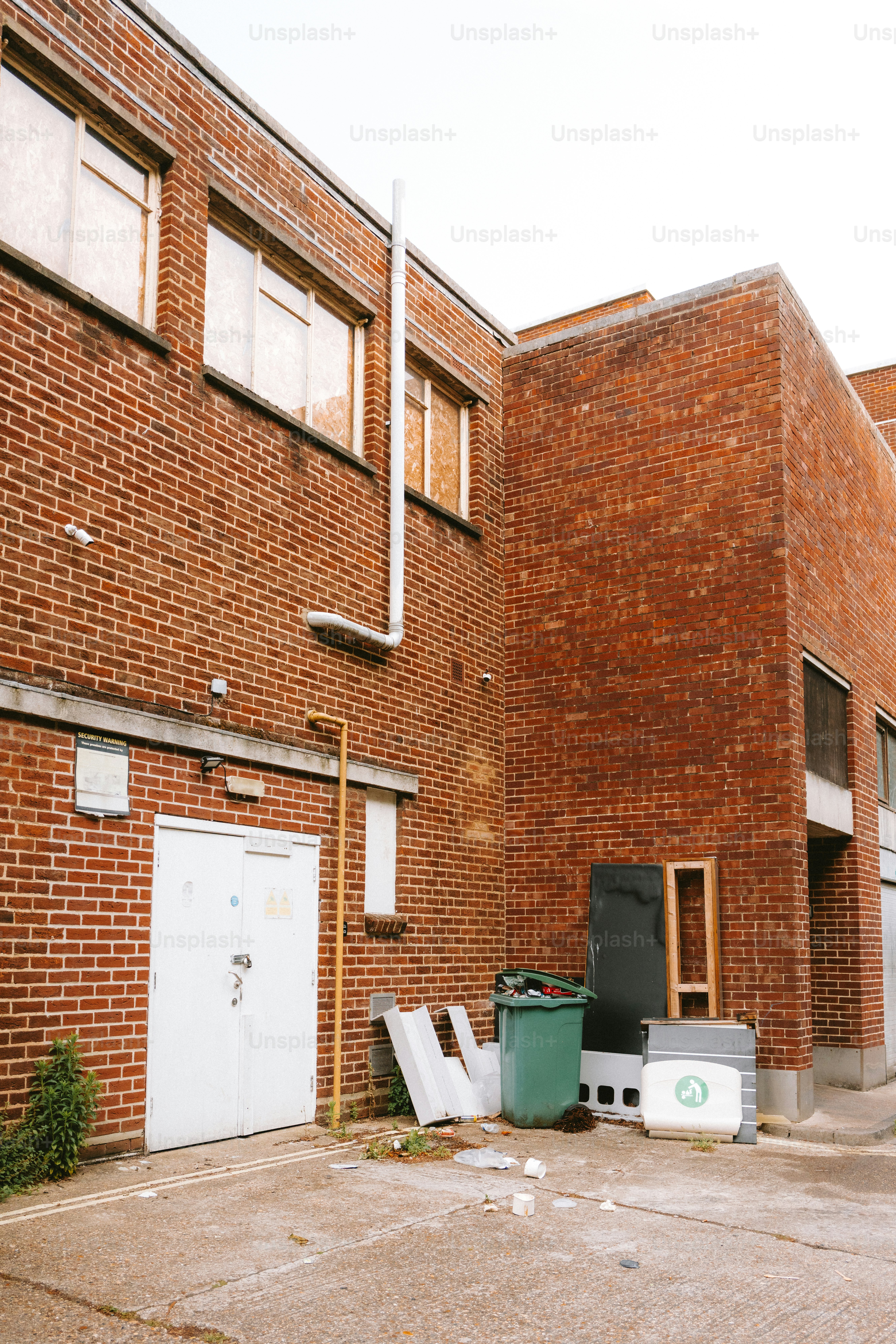 A brick building's exterior has trash and debris.