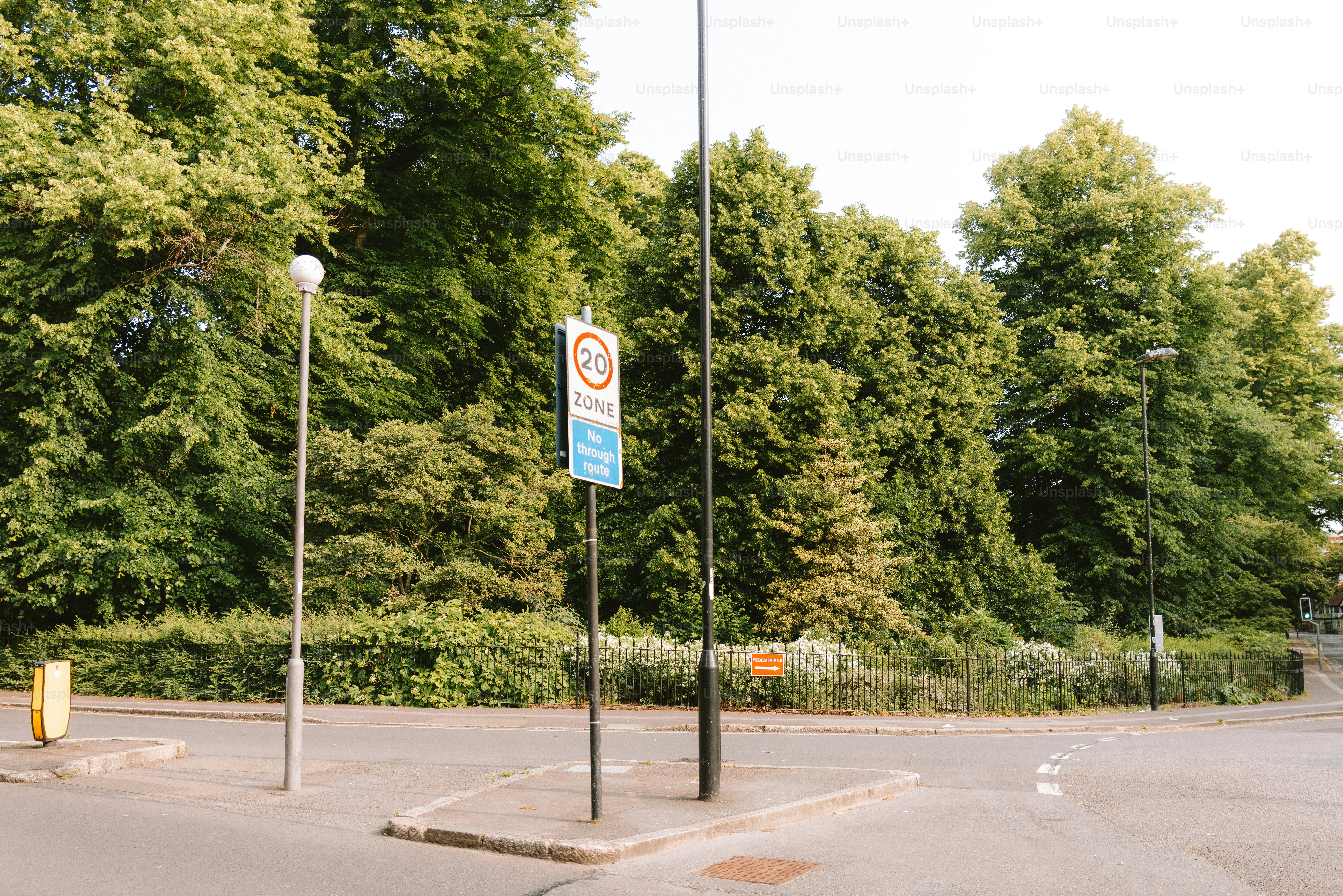 A street sign stands in front of lush green trees.