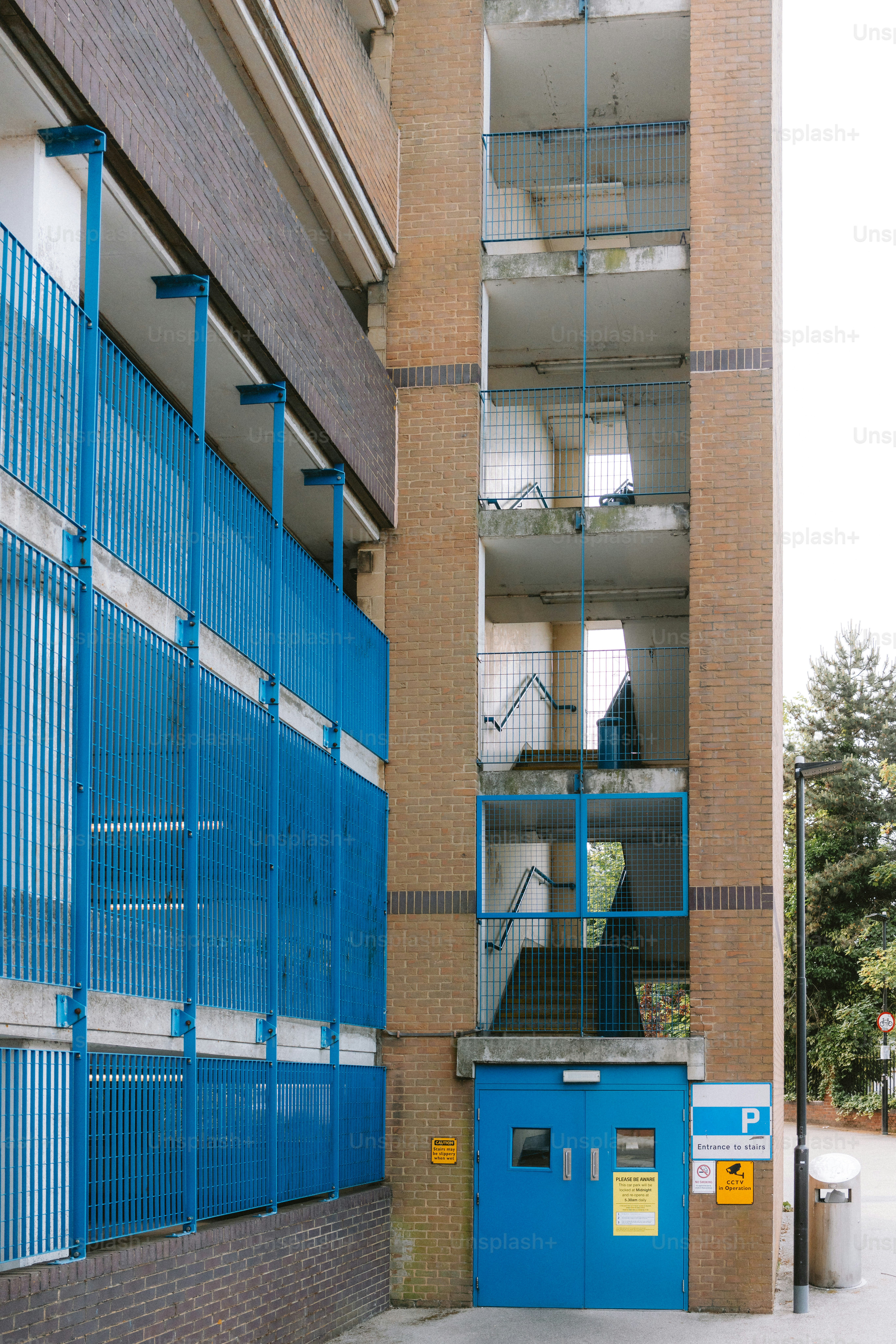 An apartment building showcases open stairwells and blue railings.