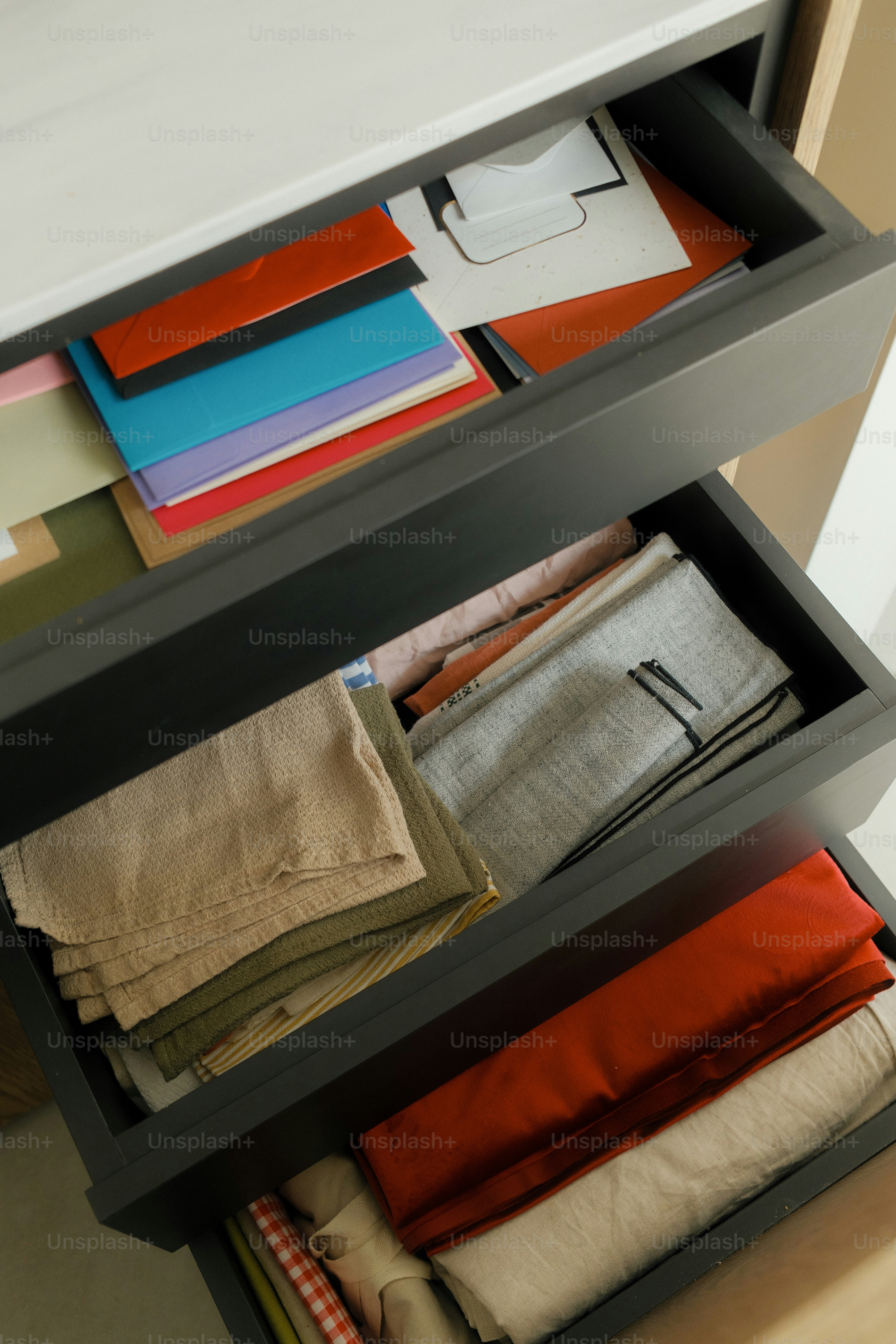 Drawers hold various fabrics and colorful papers.