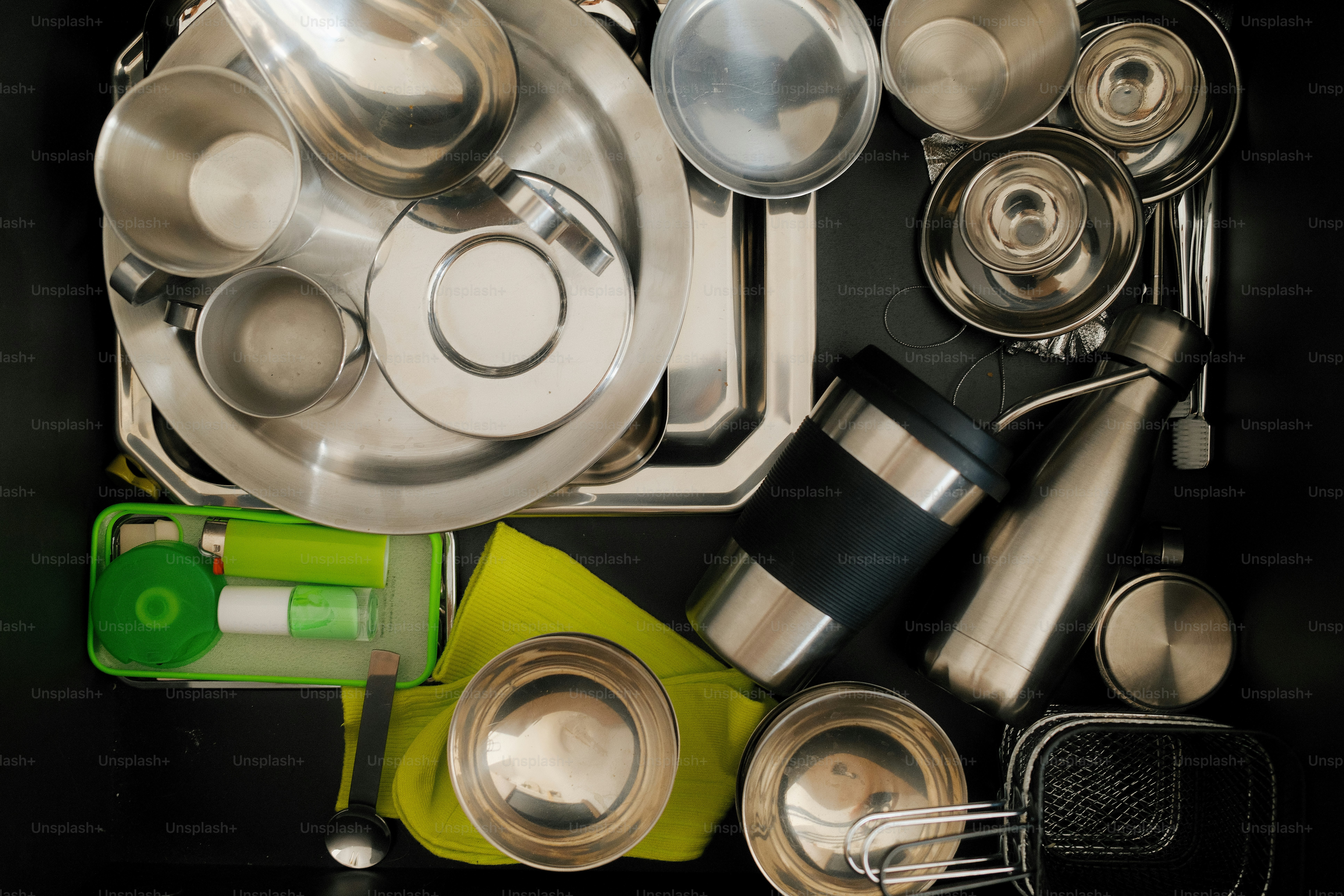 Stainless steel dishware is neatly arranged in a drawer.