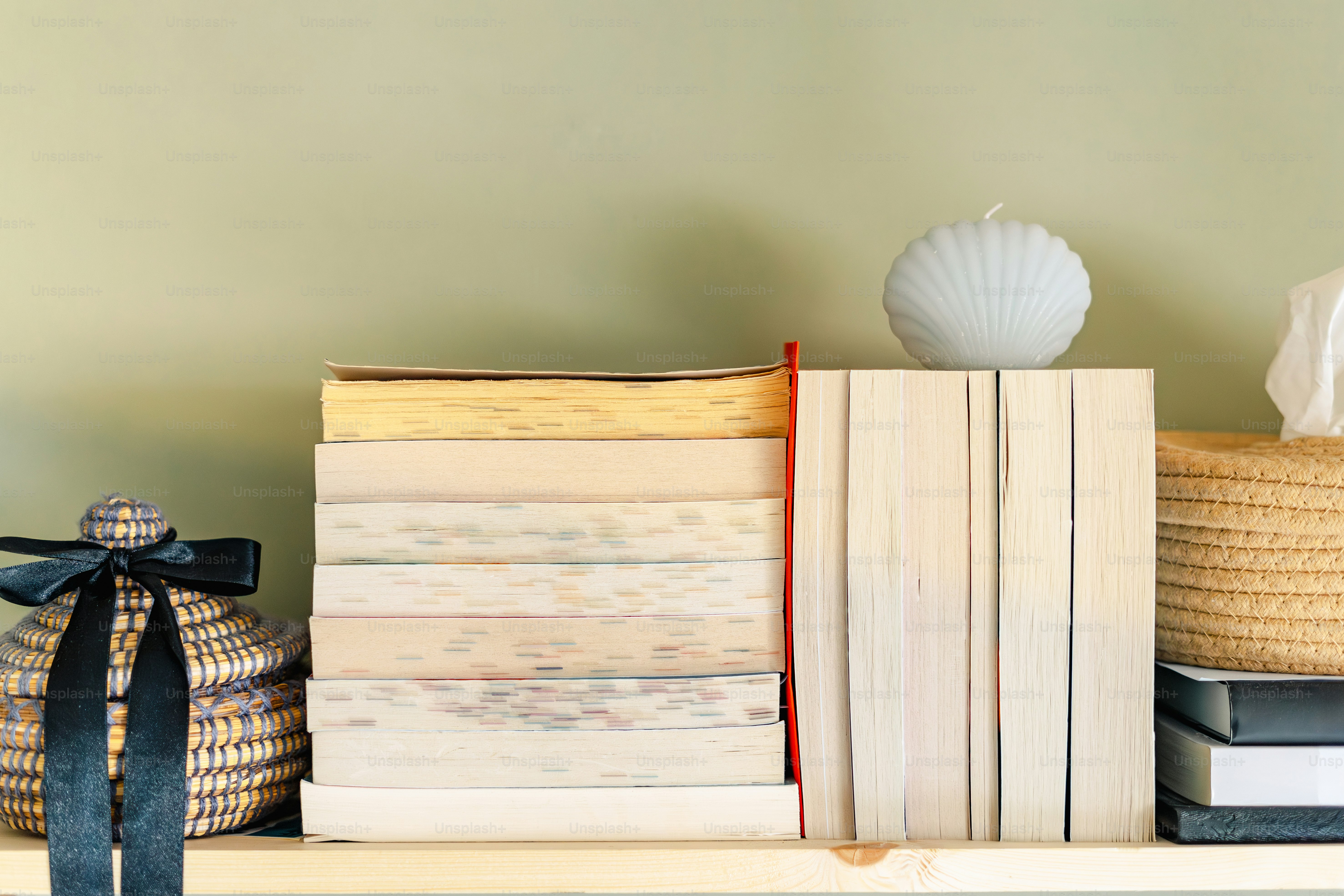 Bücher, Kerze und Korb auf einem Holzregal.