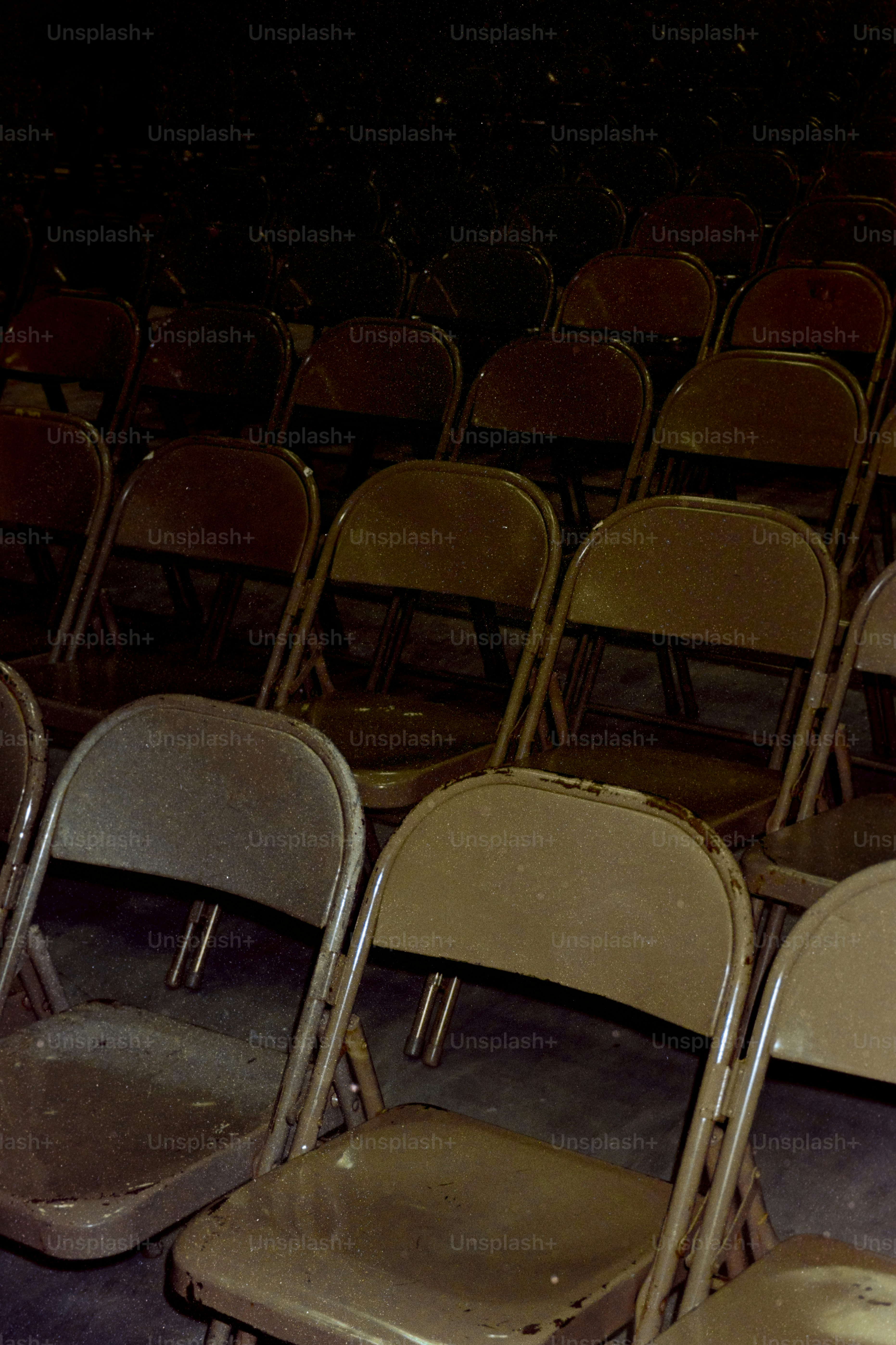 Rows of empty metal chairs in a dimly lit room.