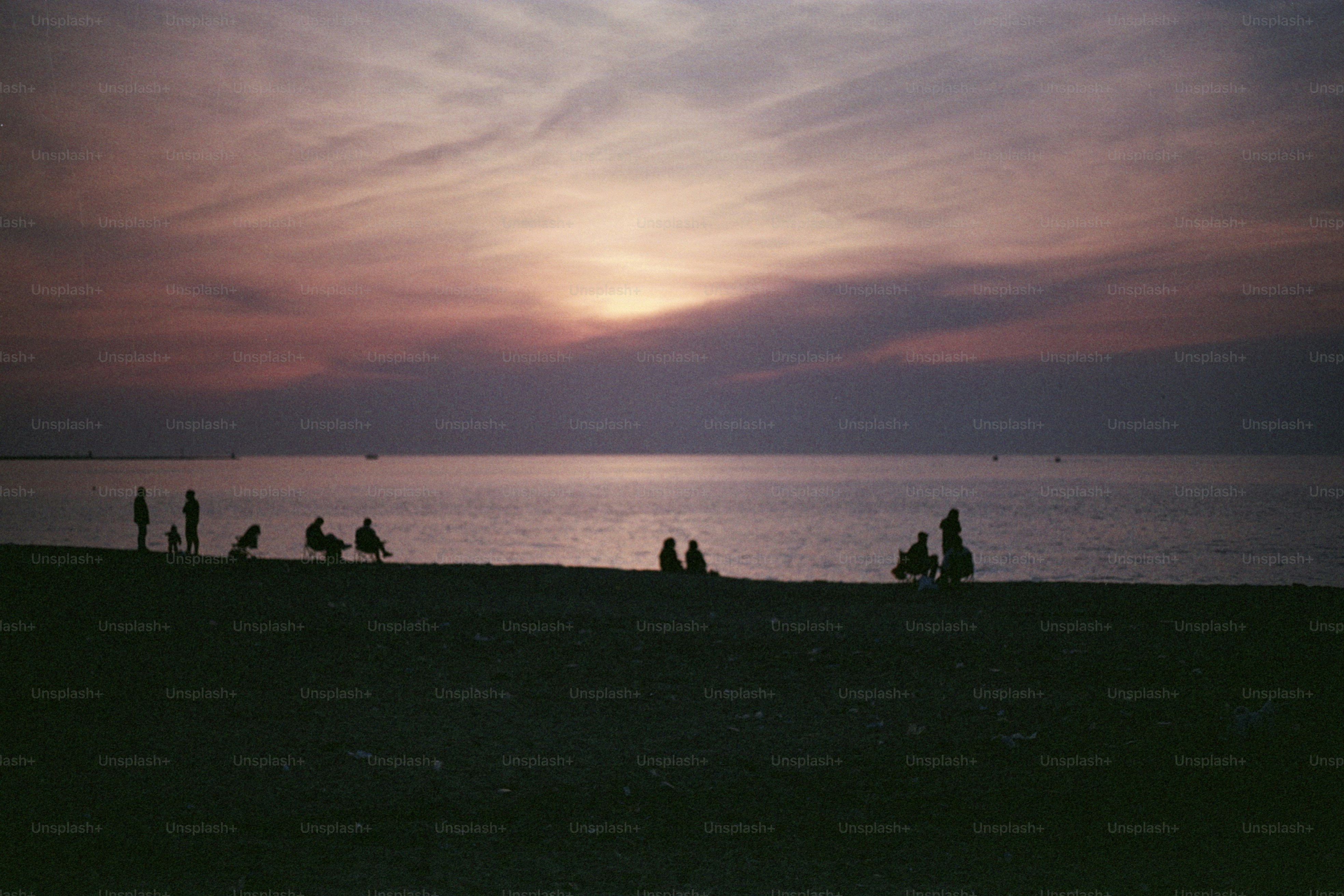 Le persone si godono il tramonto in spiaggia.