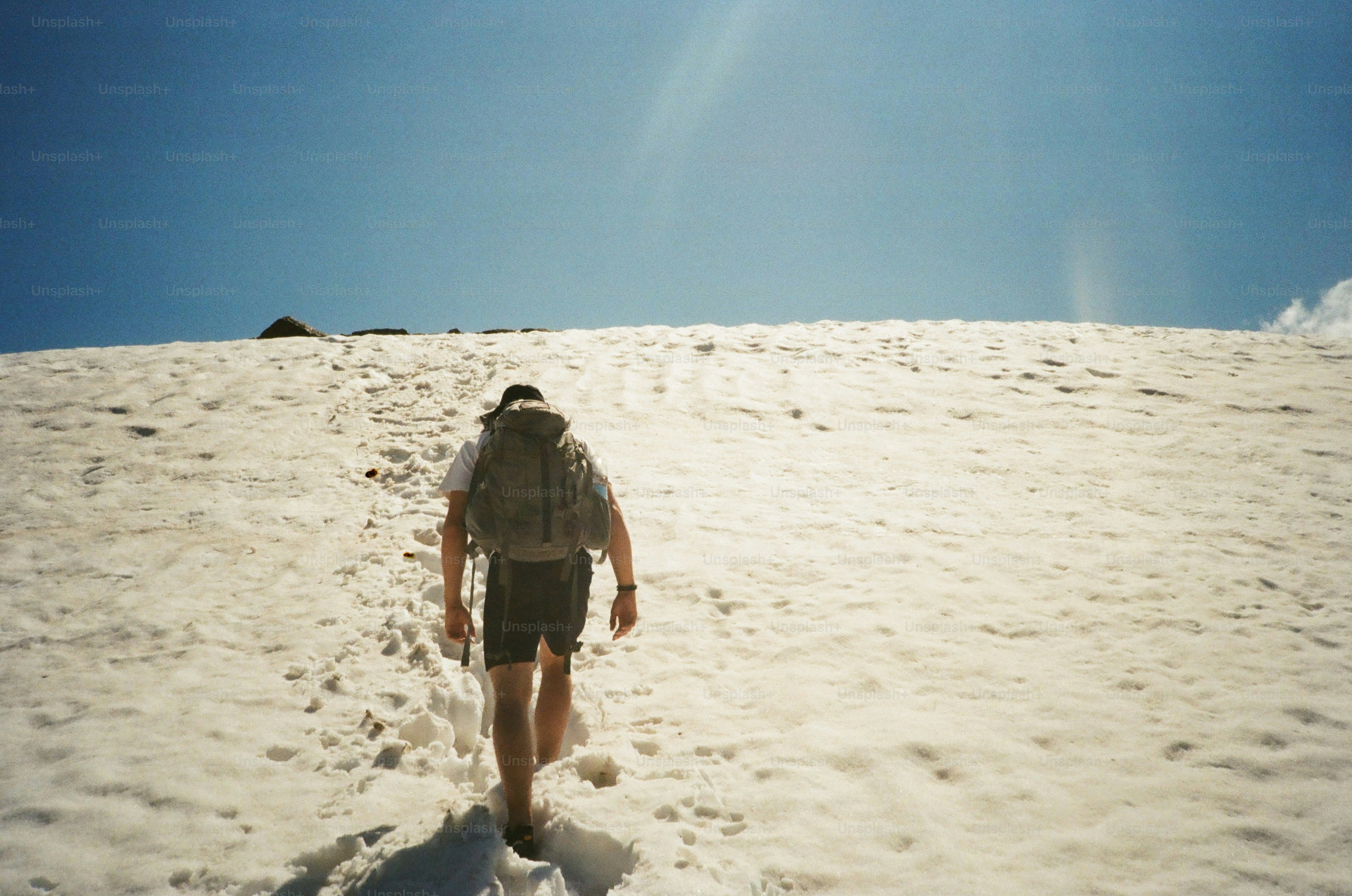Un excursionista asciende una montaña cubierta de nieve.