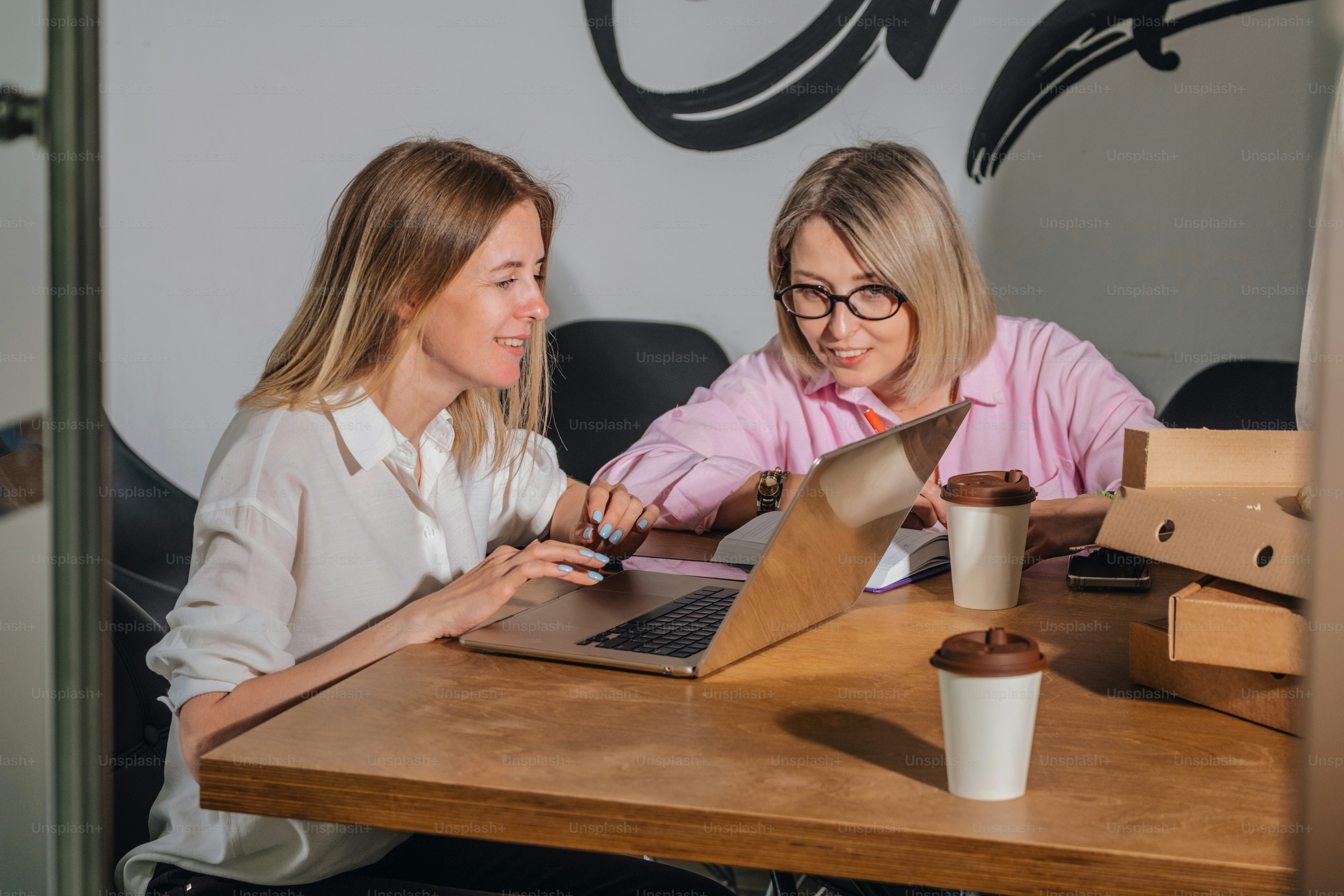 Duas mulheres colaboram juntas em um laptop.
