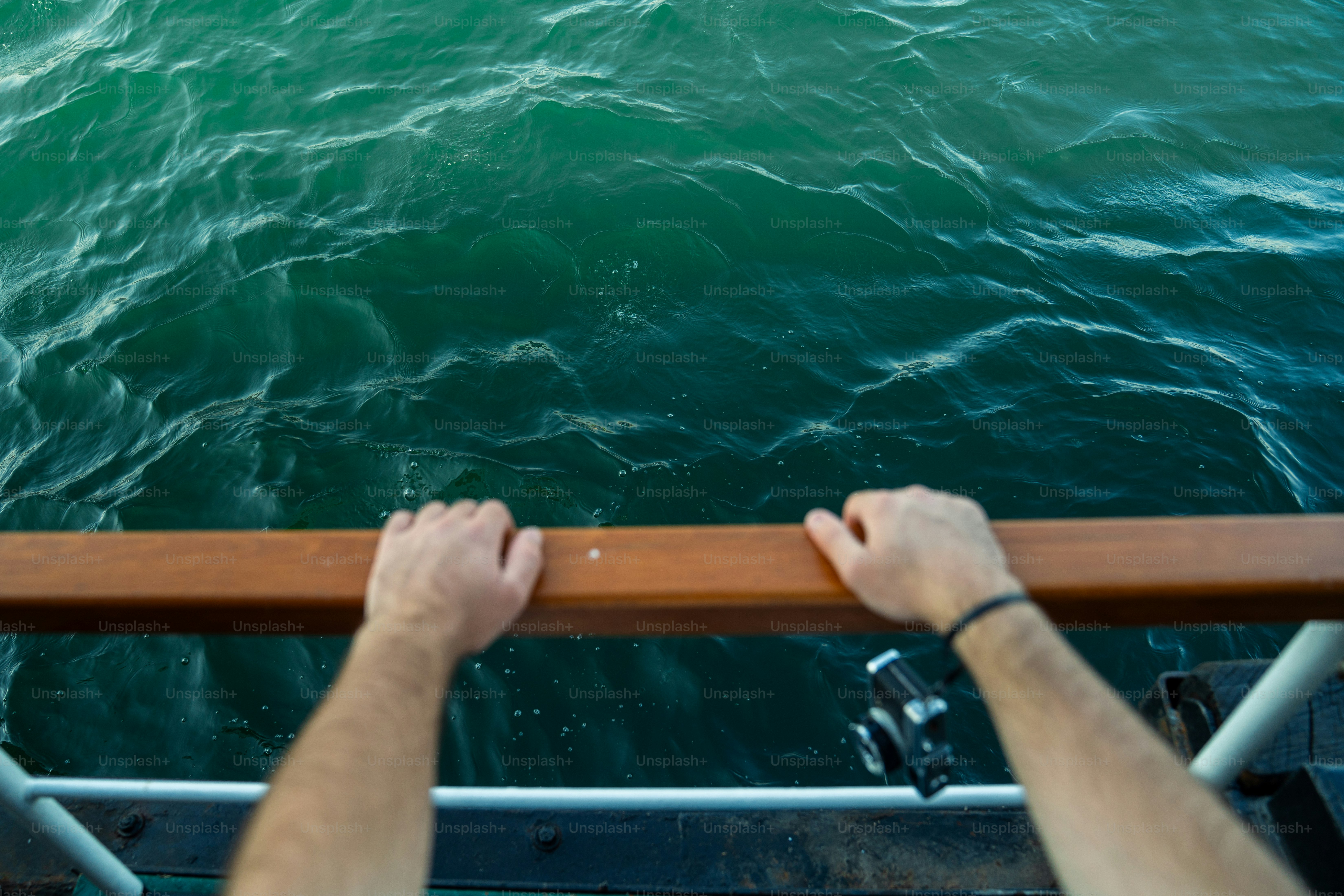 Hands gripping a railing above the ocean water. photo – View Image on ...