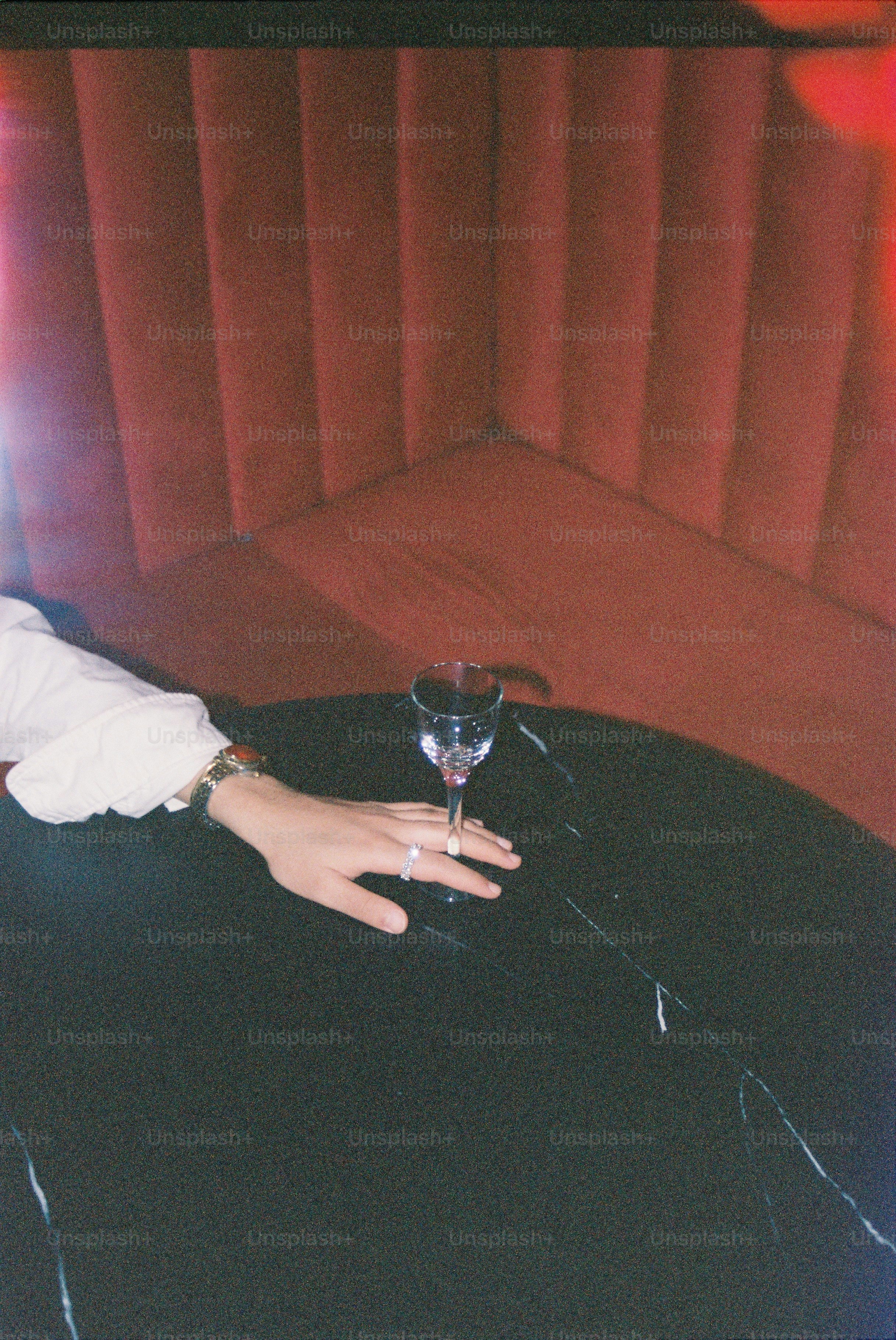 Hand with a wine glass on a dark table.