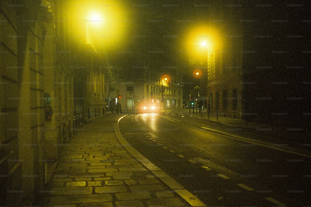 A wet street glitters under dim streetlights at night.