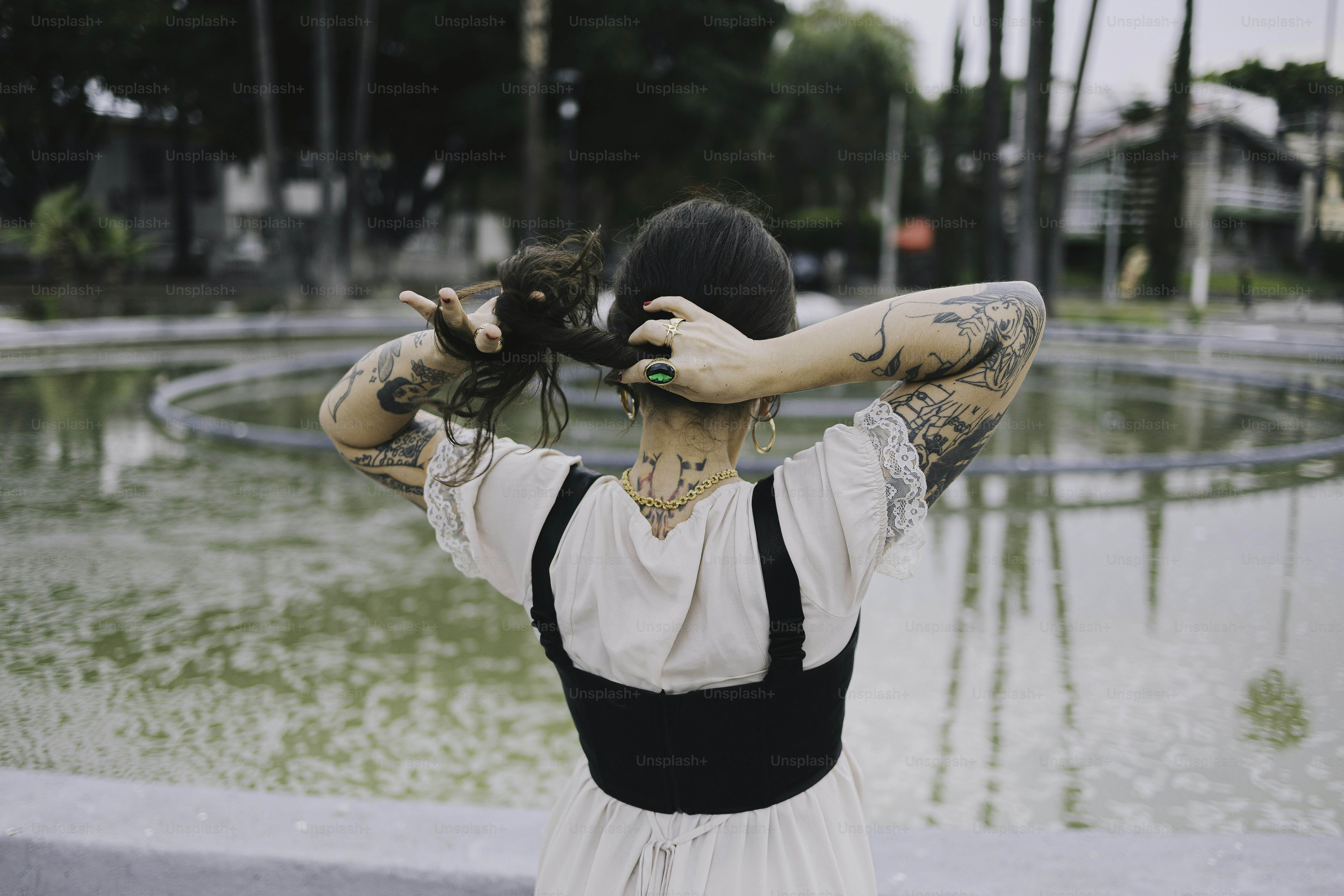 Woman with tattoos tying up her hair.