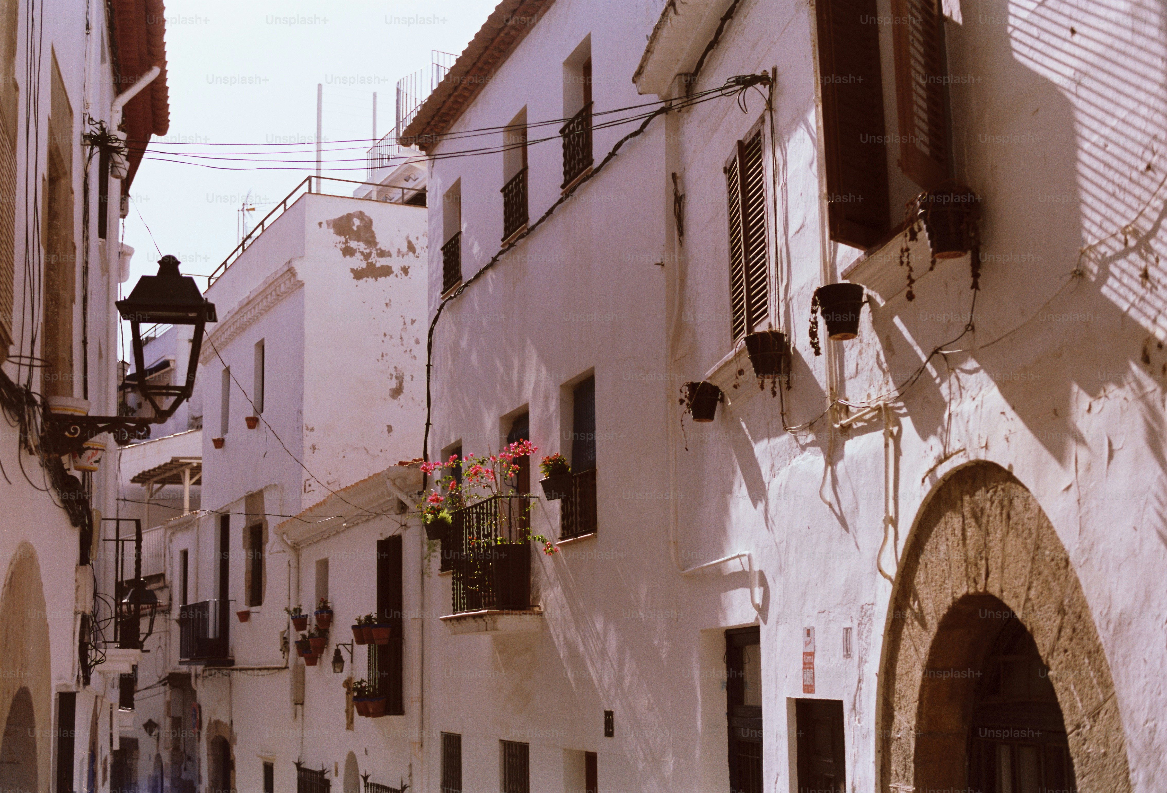 A narrow street with white buildings in sunlight.