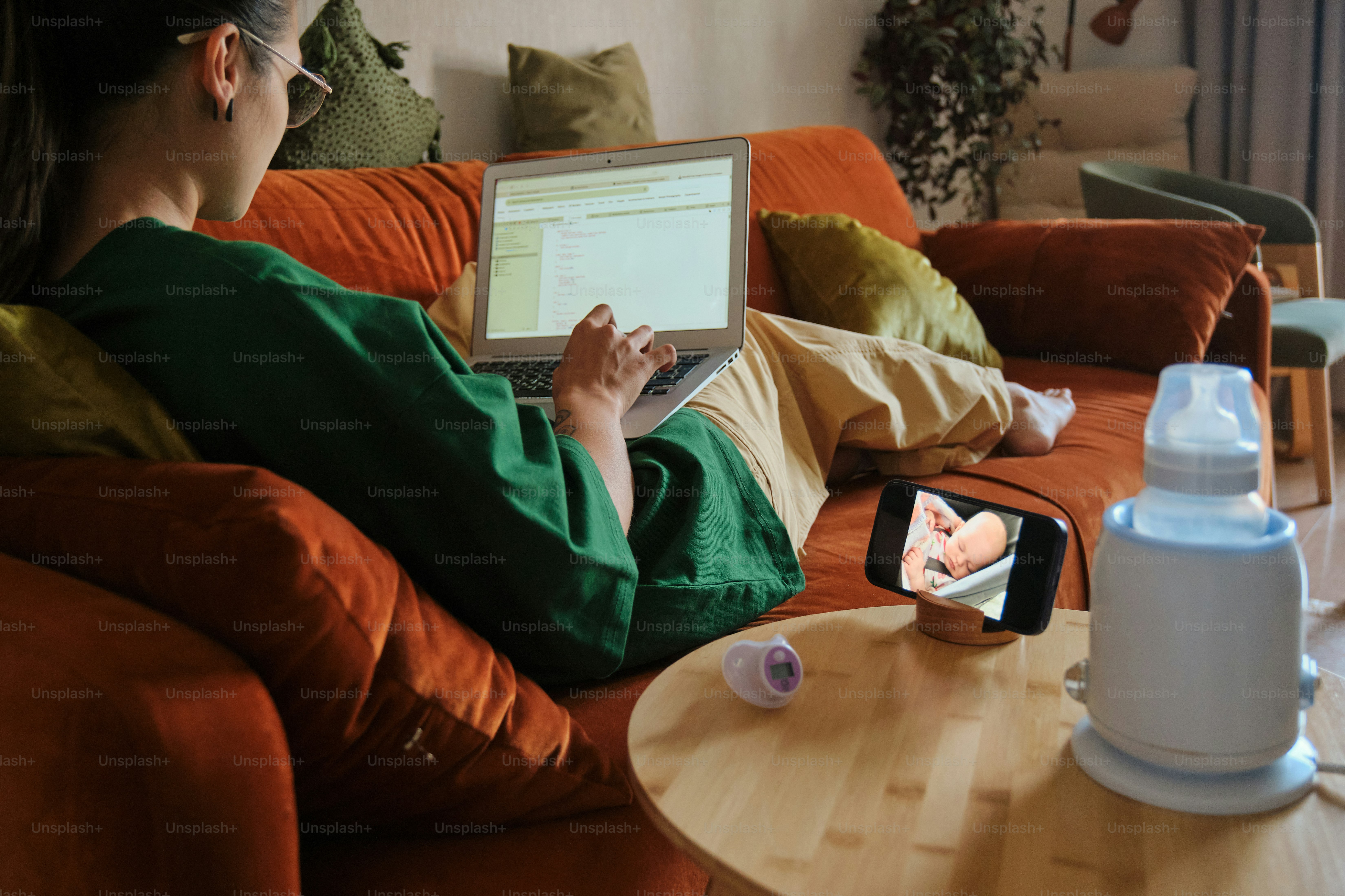 Mom works remotely, watching her baby on a phone.