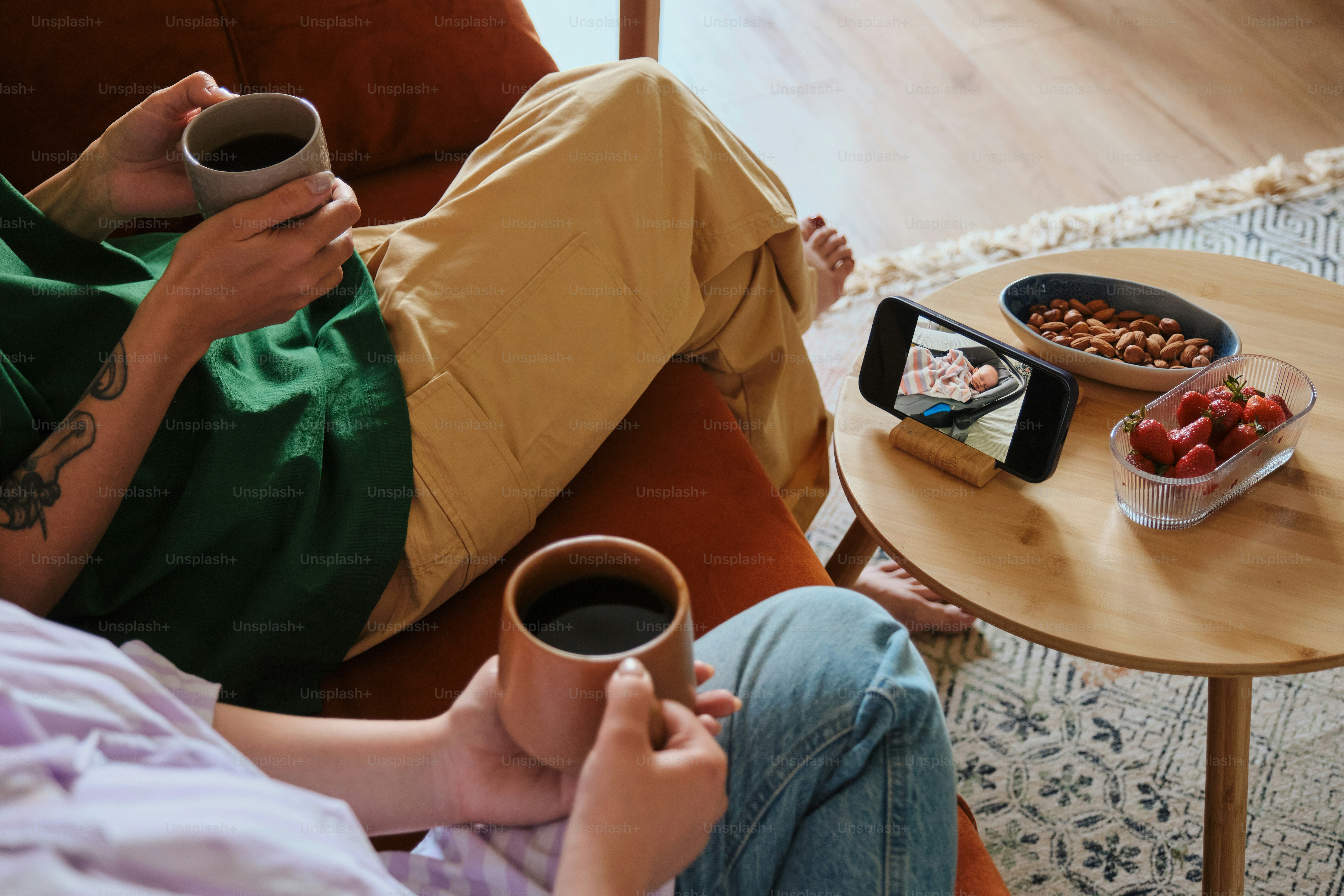 Two people enjoy coffee while watching a video.