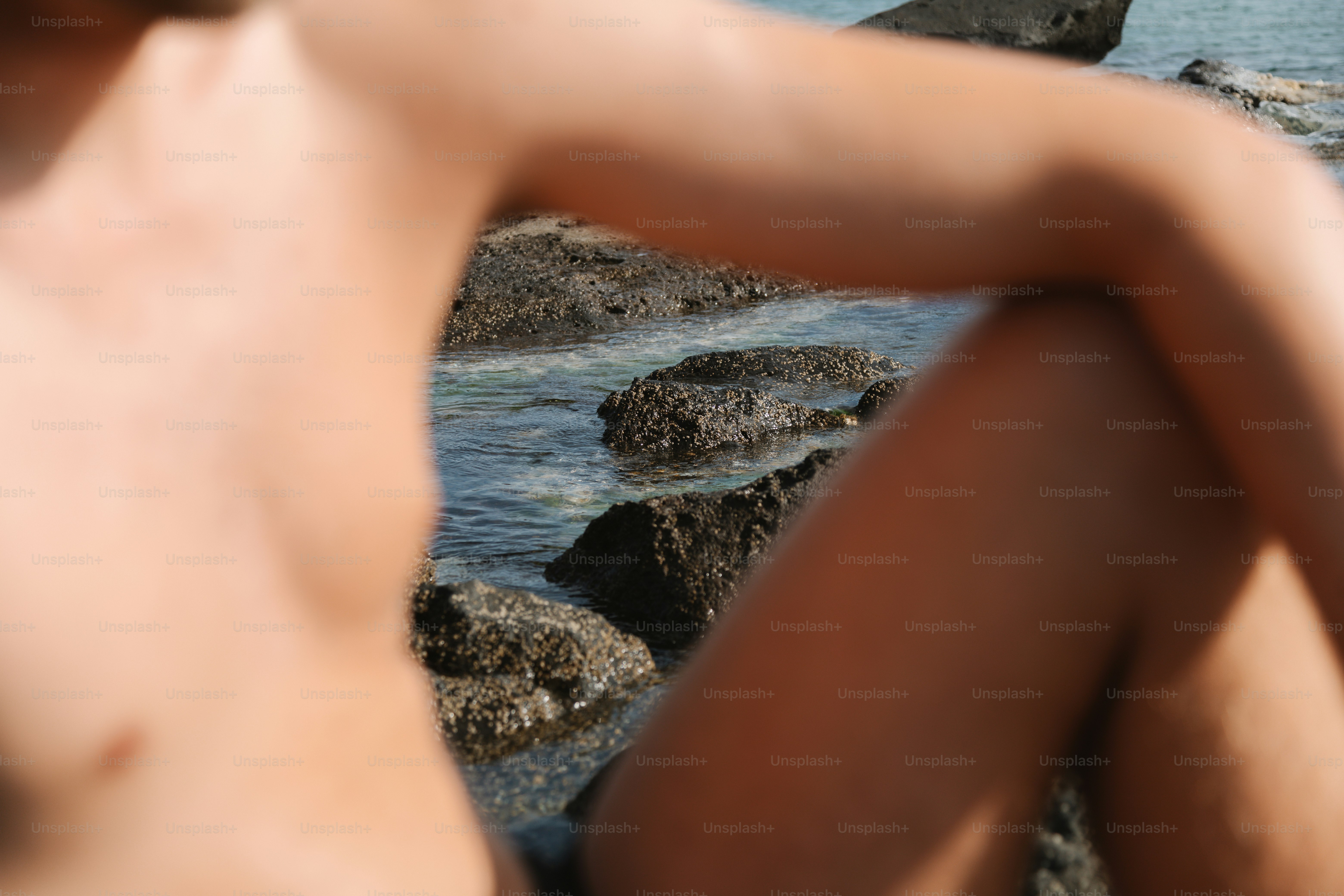 Young person sitting on rocks by the ocean