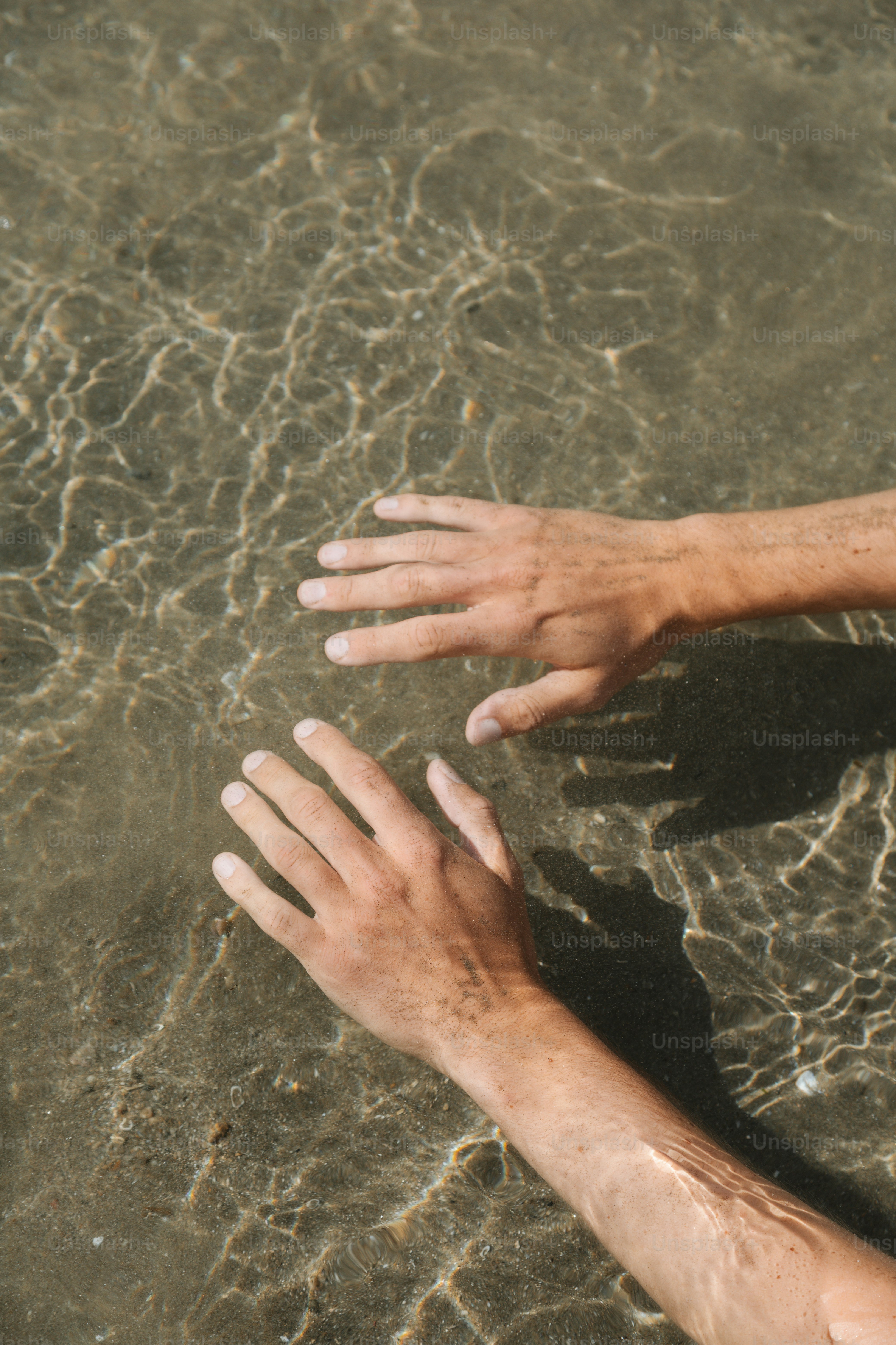 Hands rest gently in the shallow water.