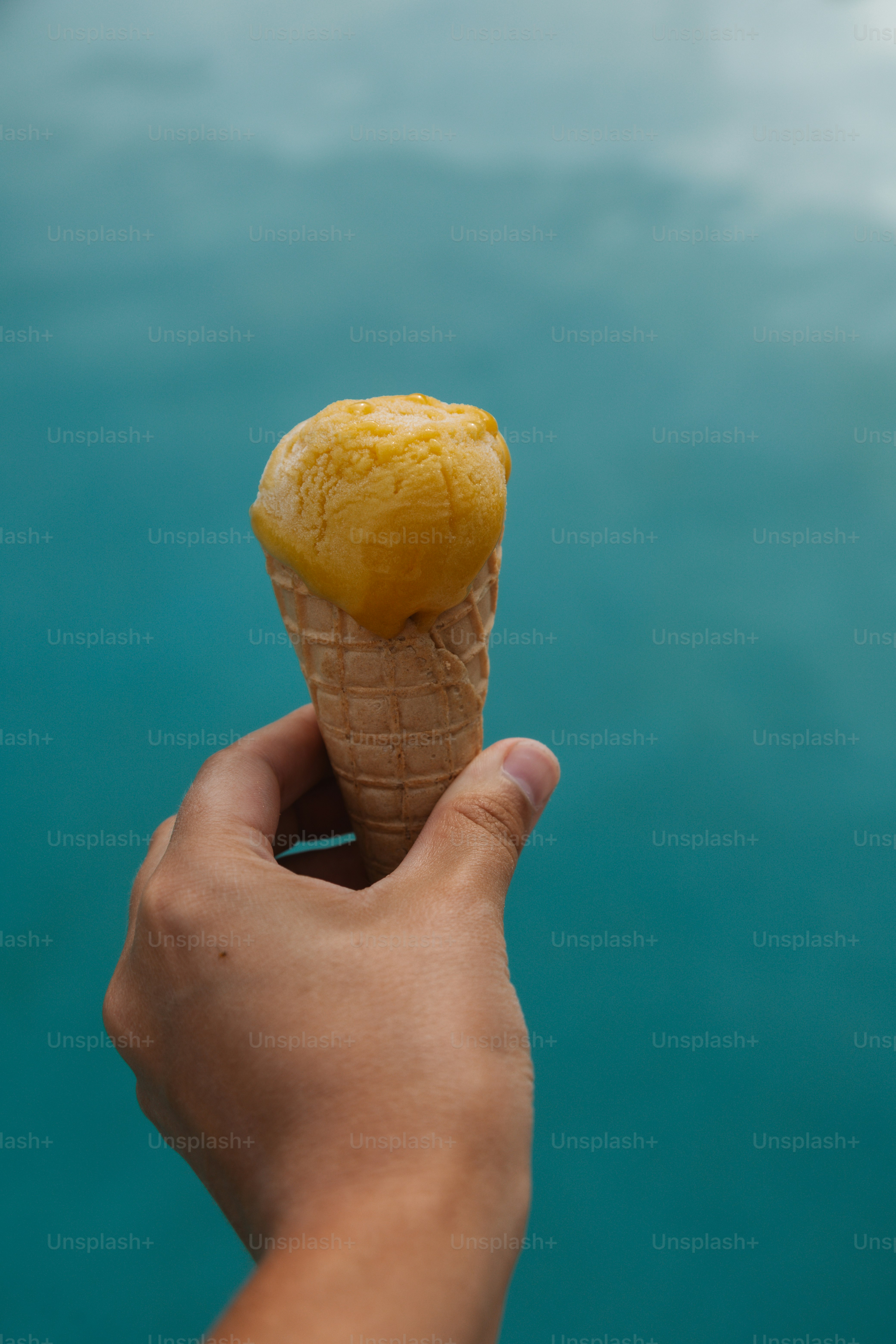 Hand holding a mango ice cream cone.