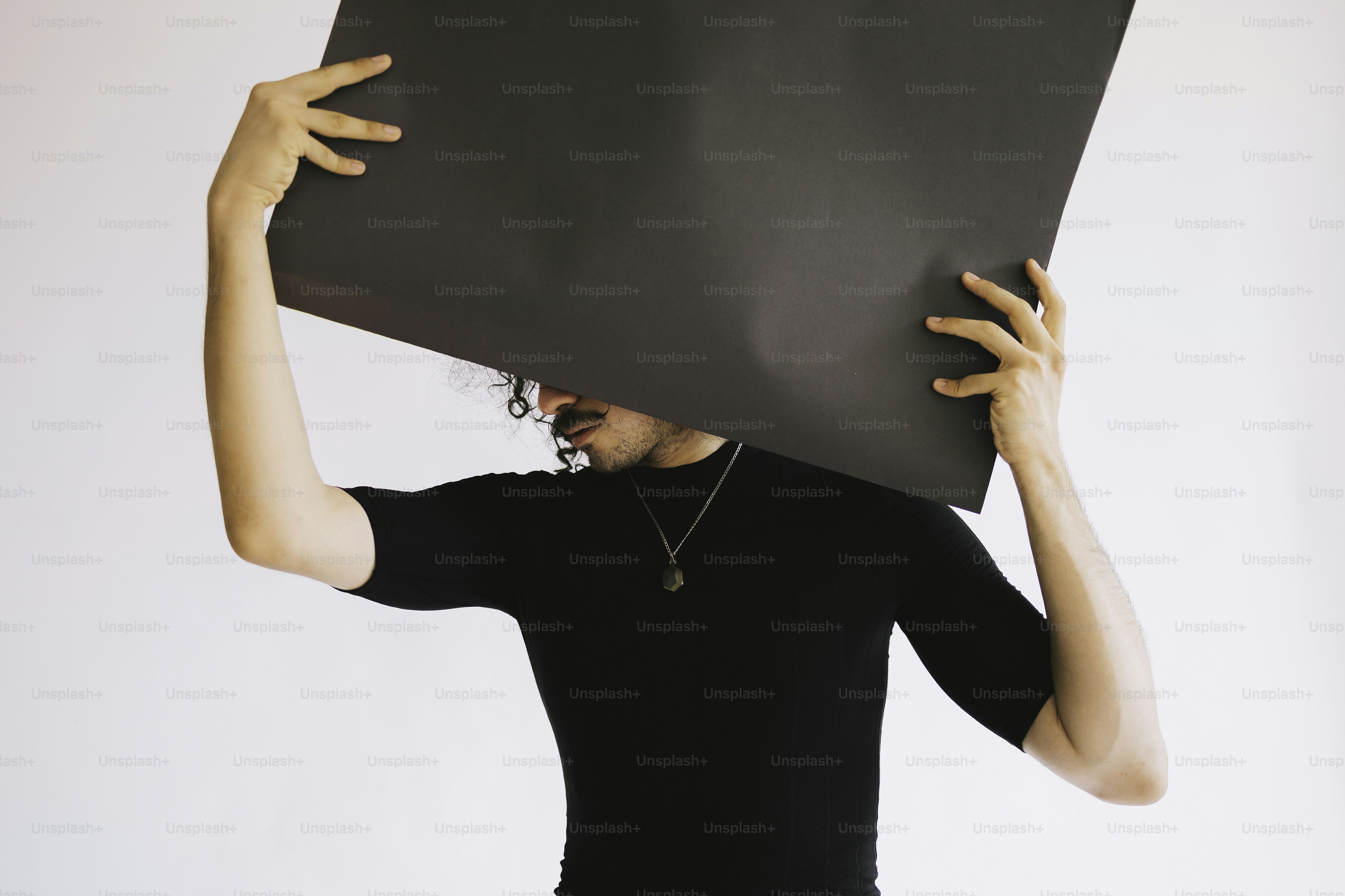 Person holds a dark rectangle in front of them.