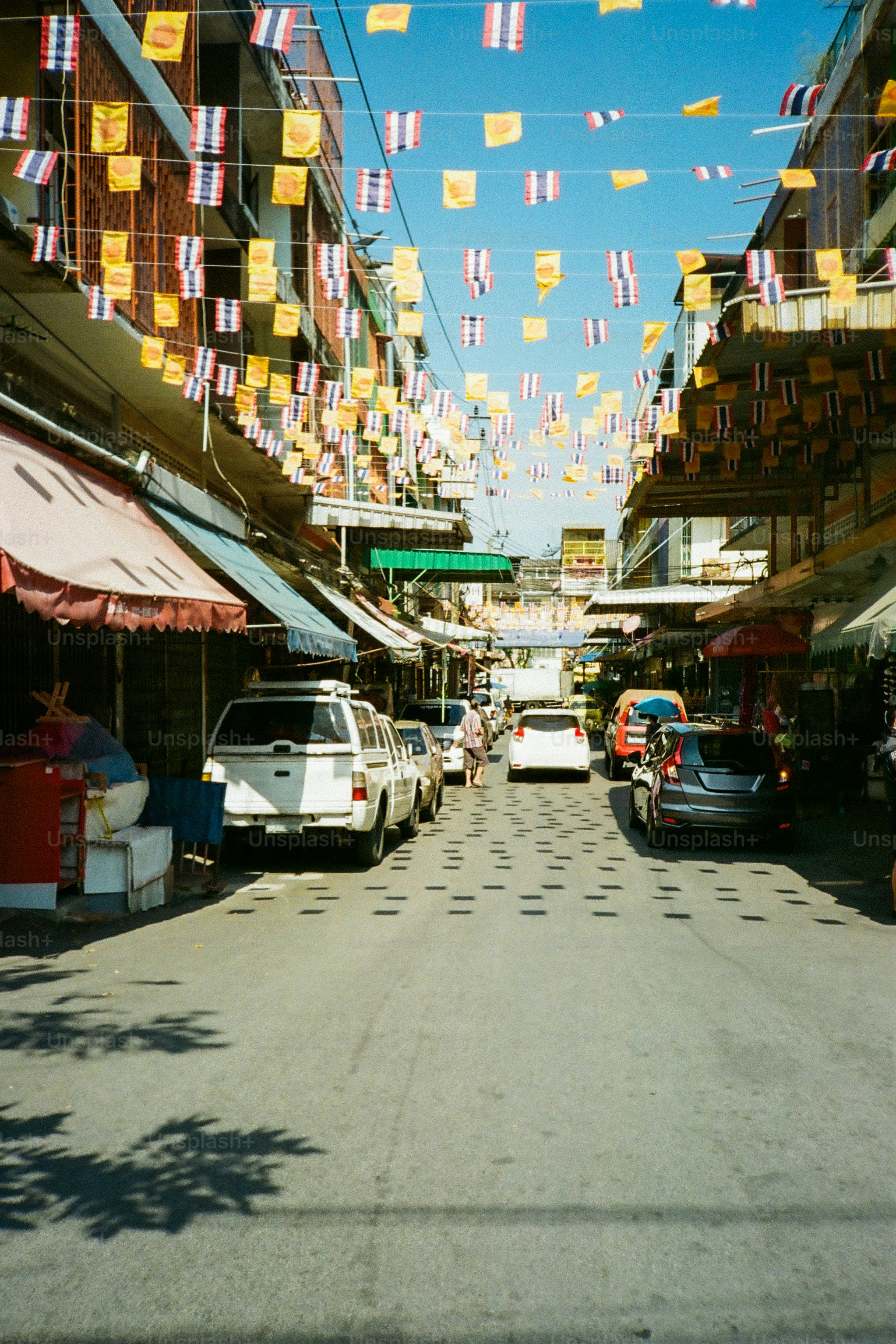 Street lined with shops and thai flags.