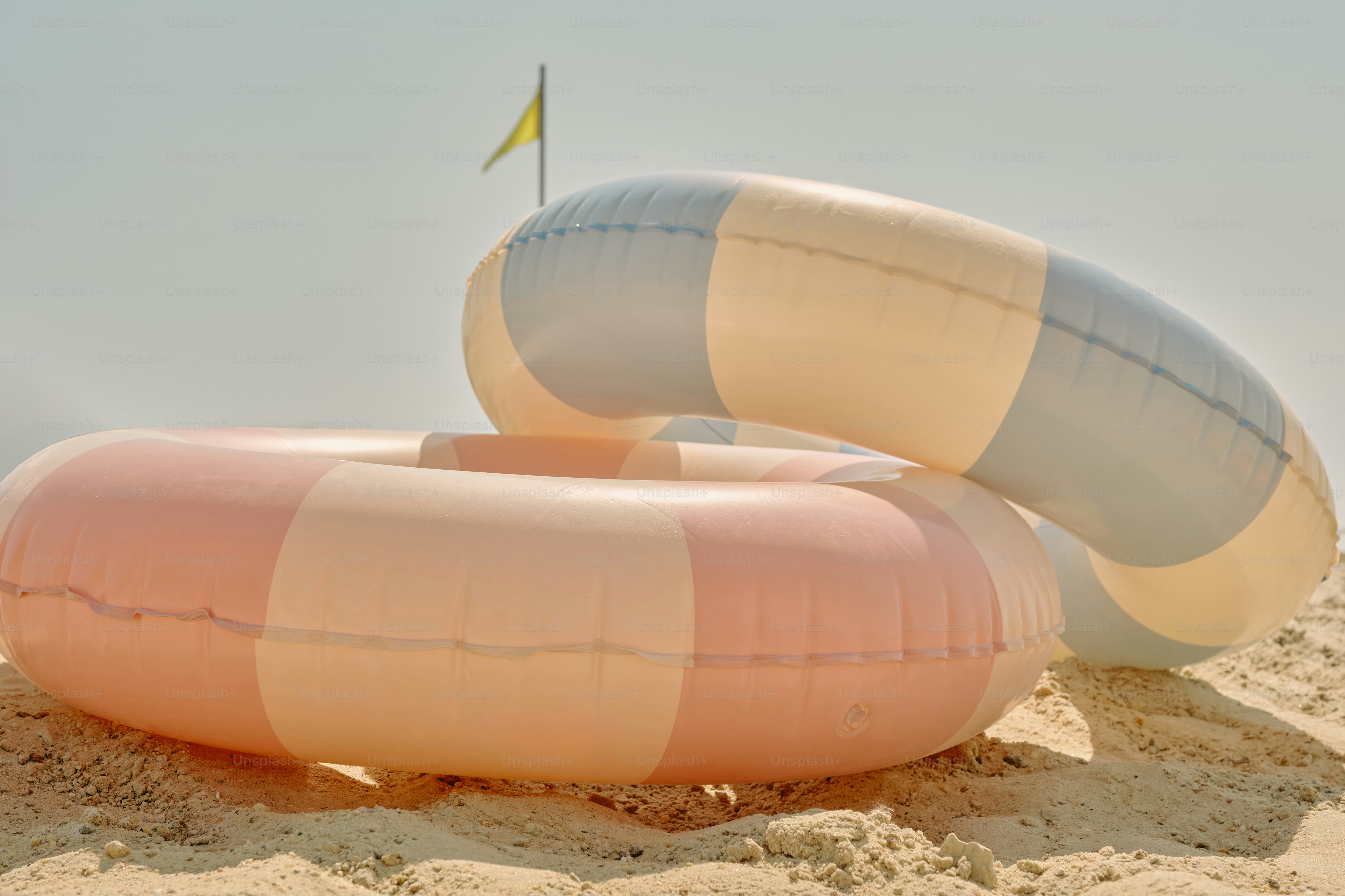 Two inflatable rings sit on a sandy beach.