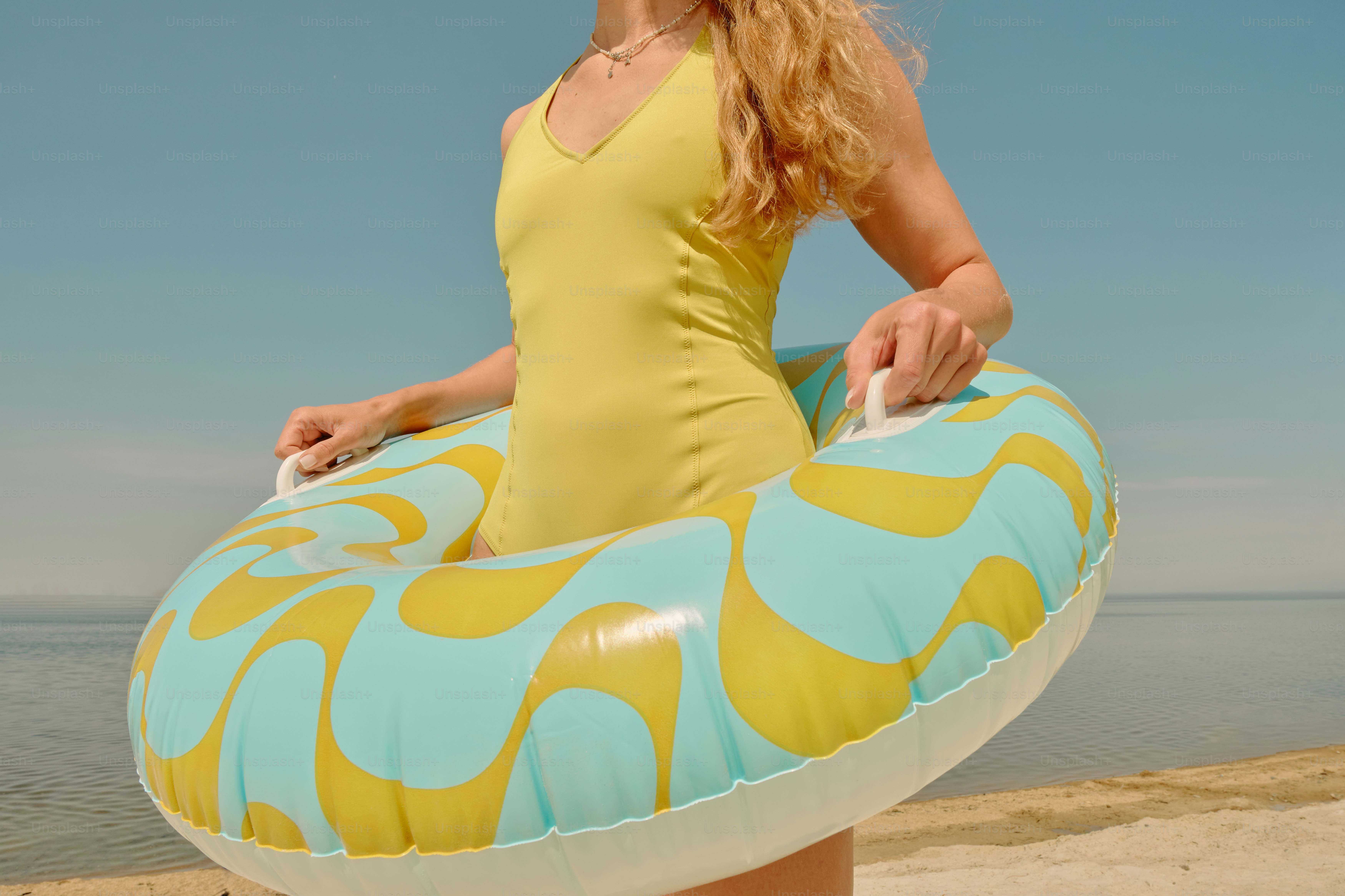 A woman relaxing on an inflatable ring at the beach. photo – Beach ...