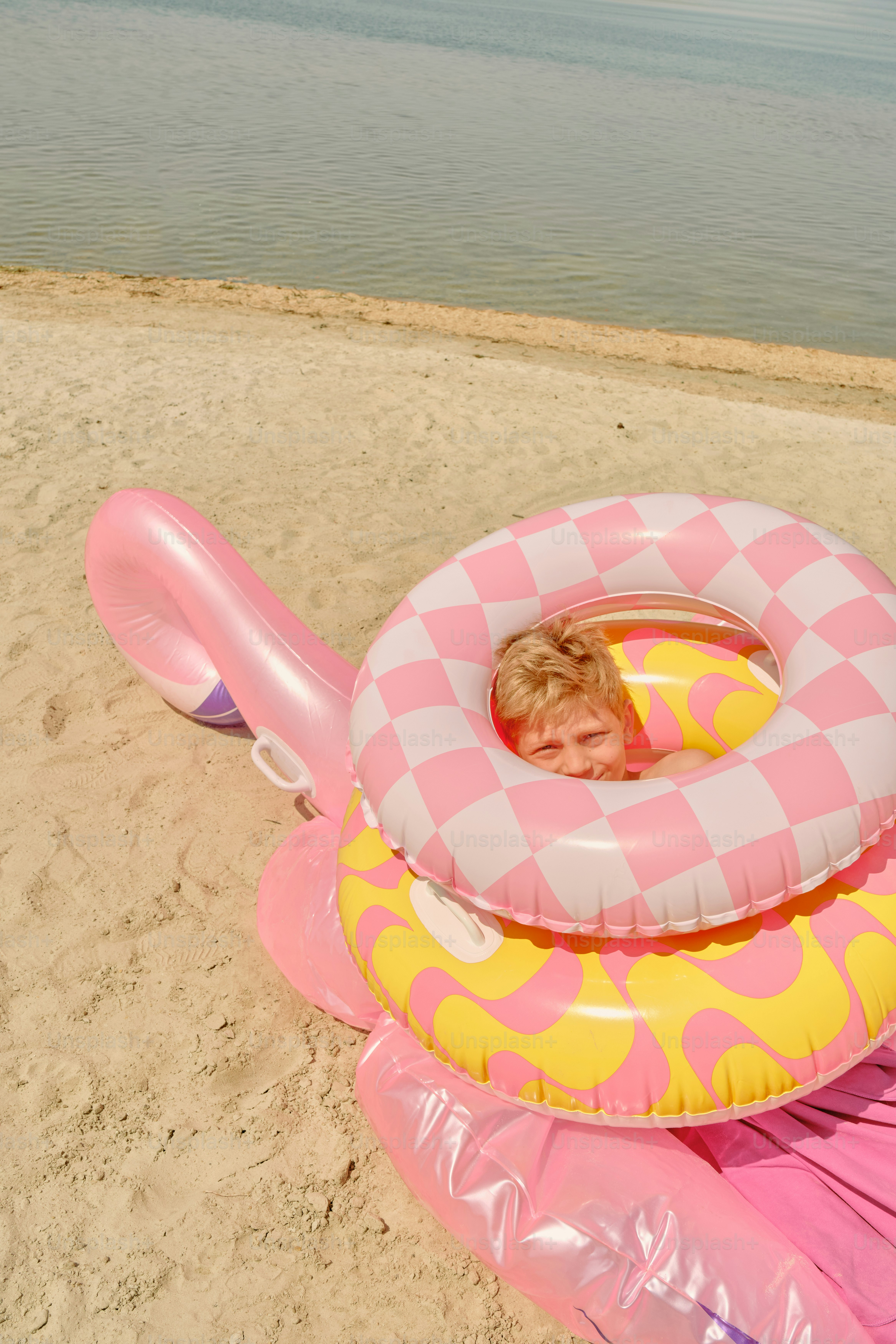 Boy enjoys a beach day inside a flamingo floatie.