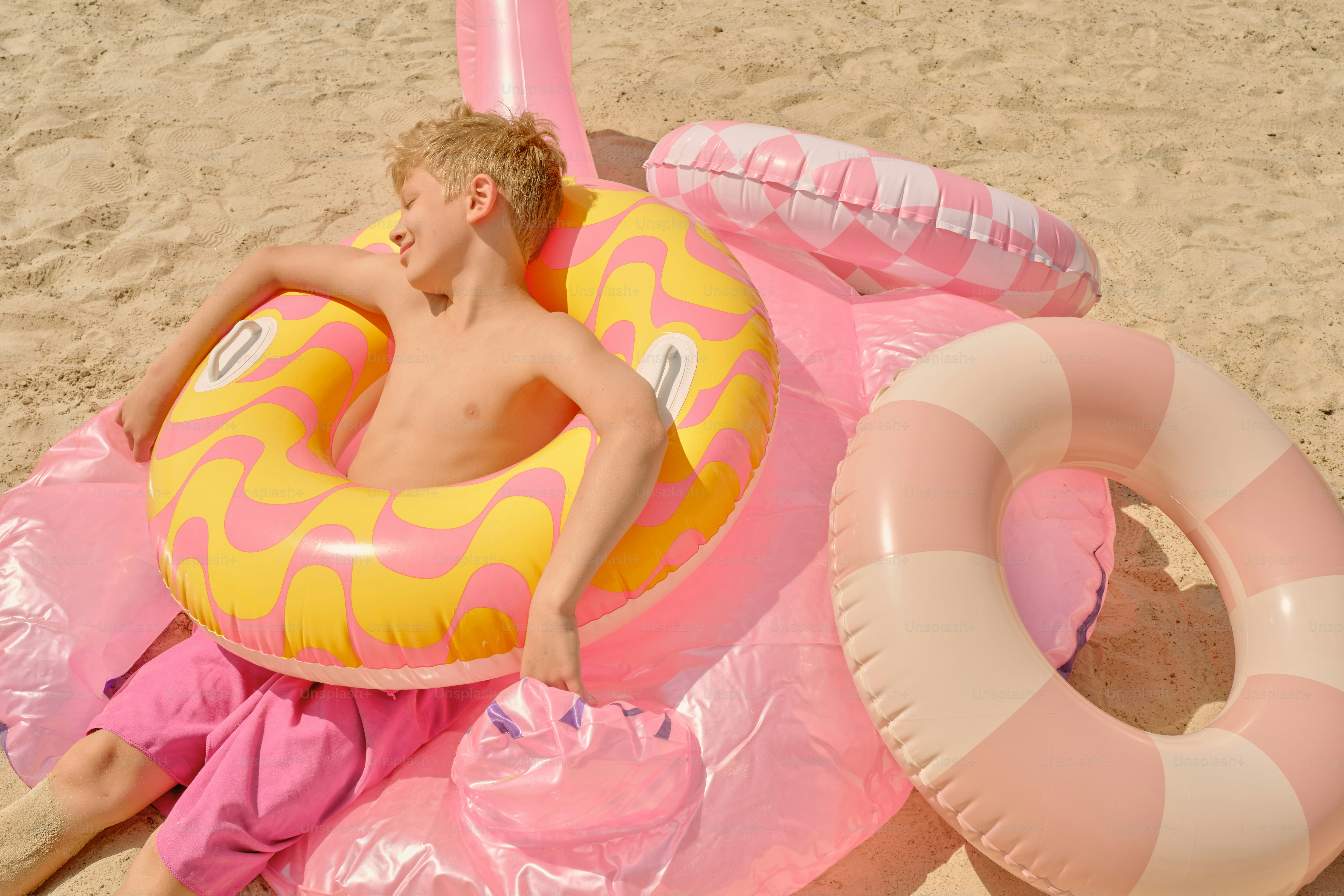 Boy relaxes on the beach with pool floats.
