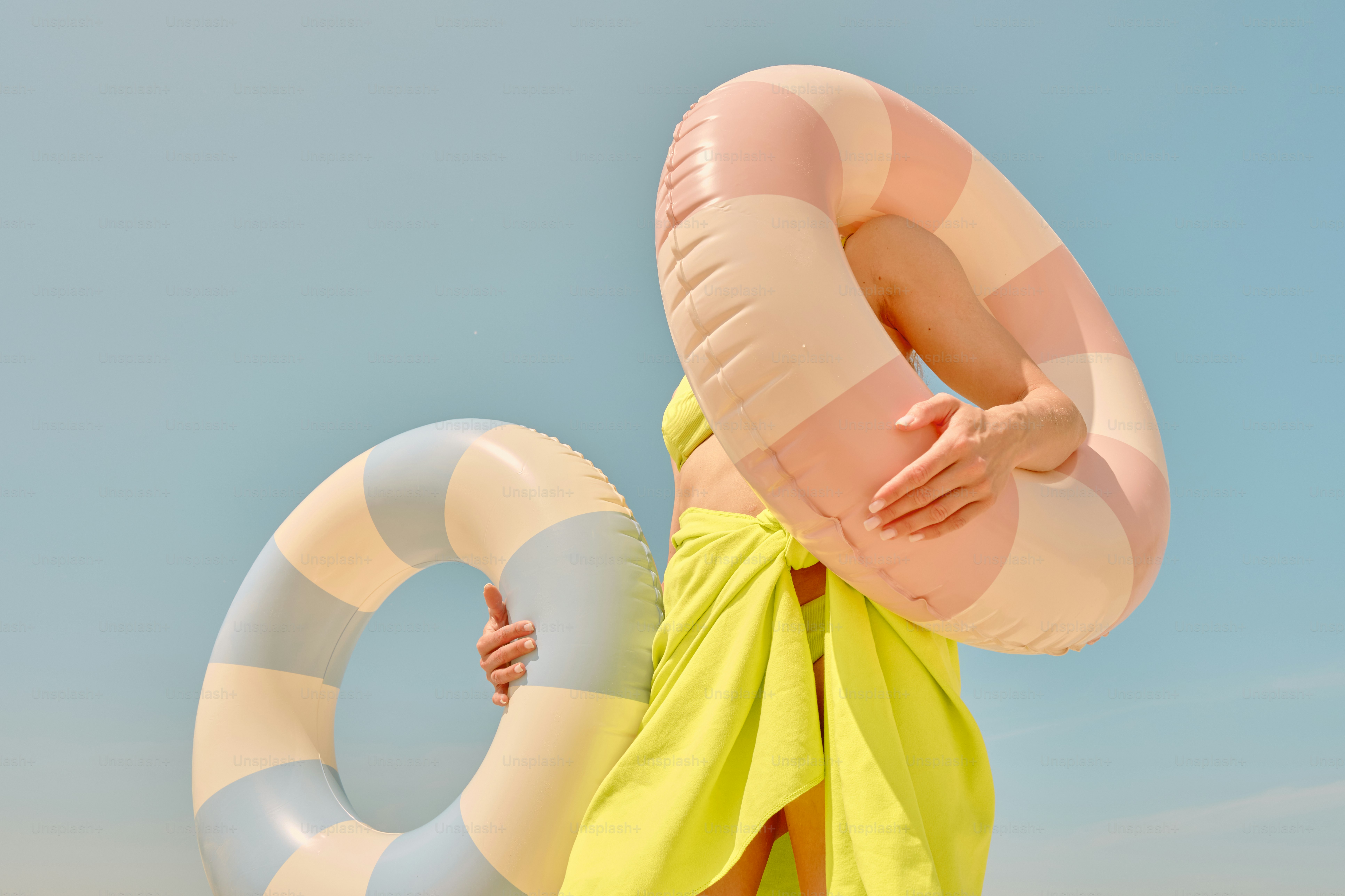 Woman holds two colorful inflatable pool rings.